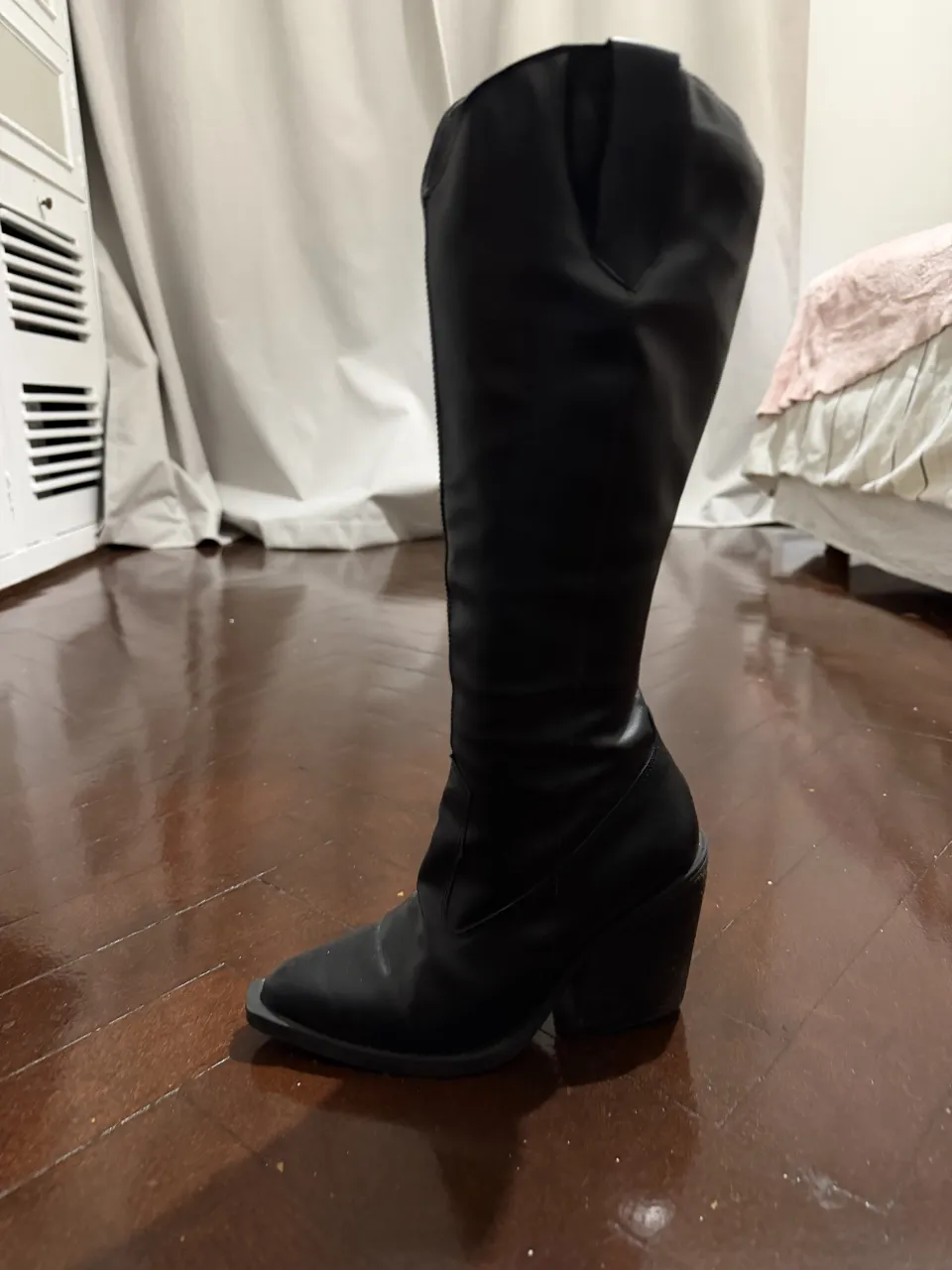 Botas negras de caña alta con taco grueso y punta fina. Cierre lateral.