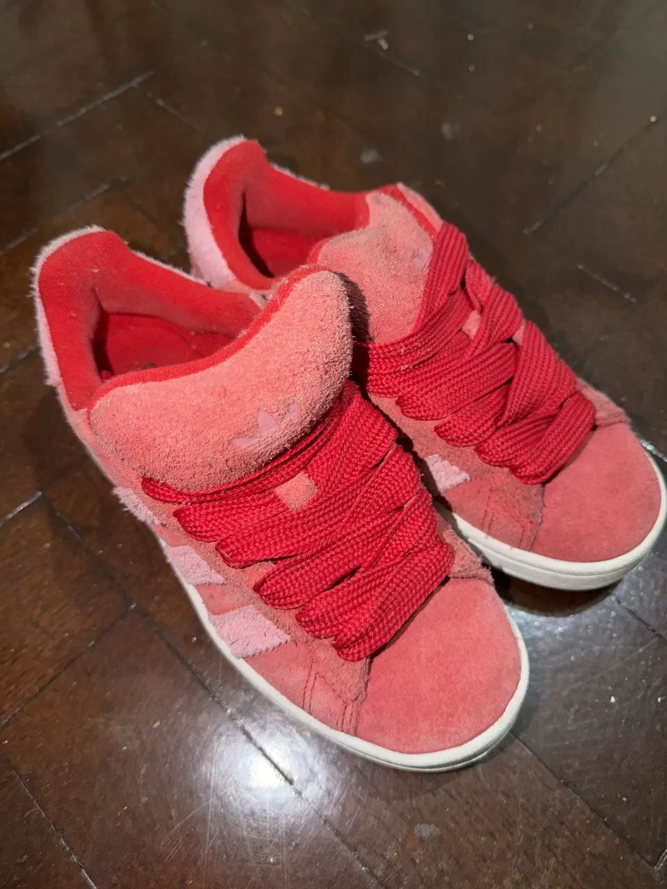 Zapatillas deportivas de gamuza en color rojo y rosa. Poseen cordones rojos y detalles de las tres tiras icónicas de la marca en los laterales.