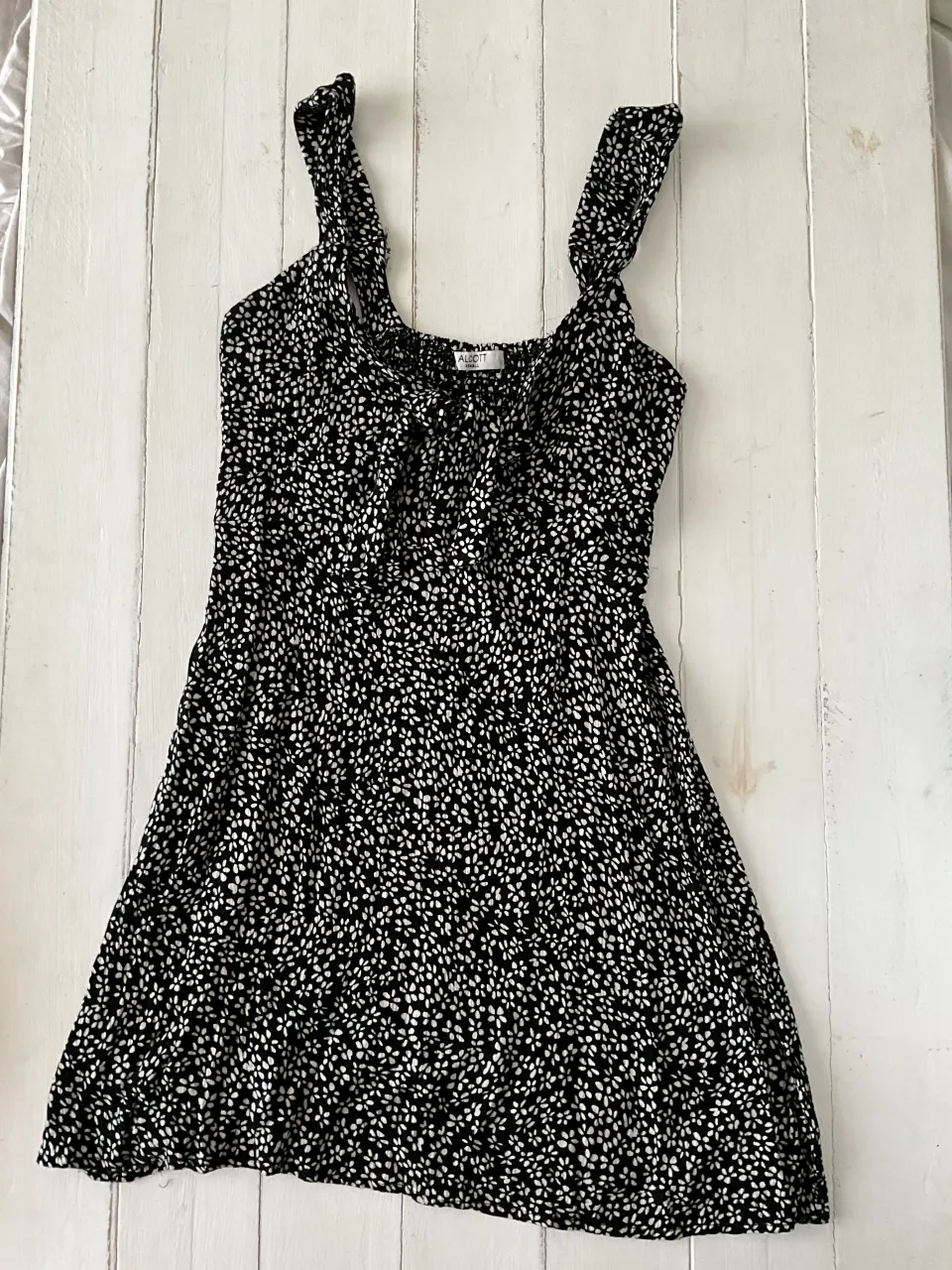 Vestido corto estampado con breteles finos y detalle de lazo en el escote.