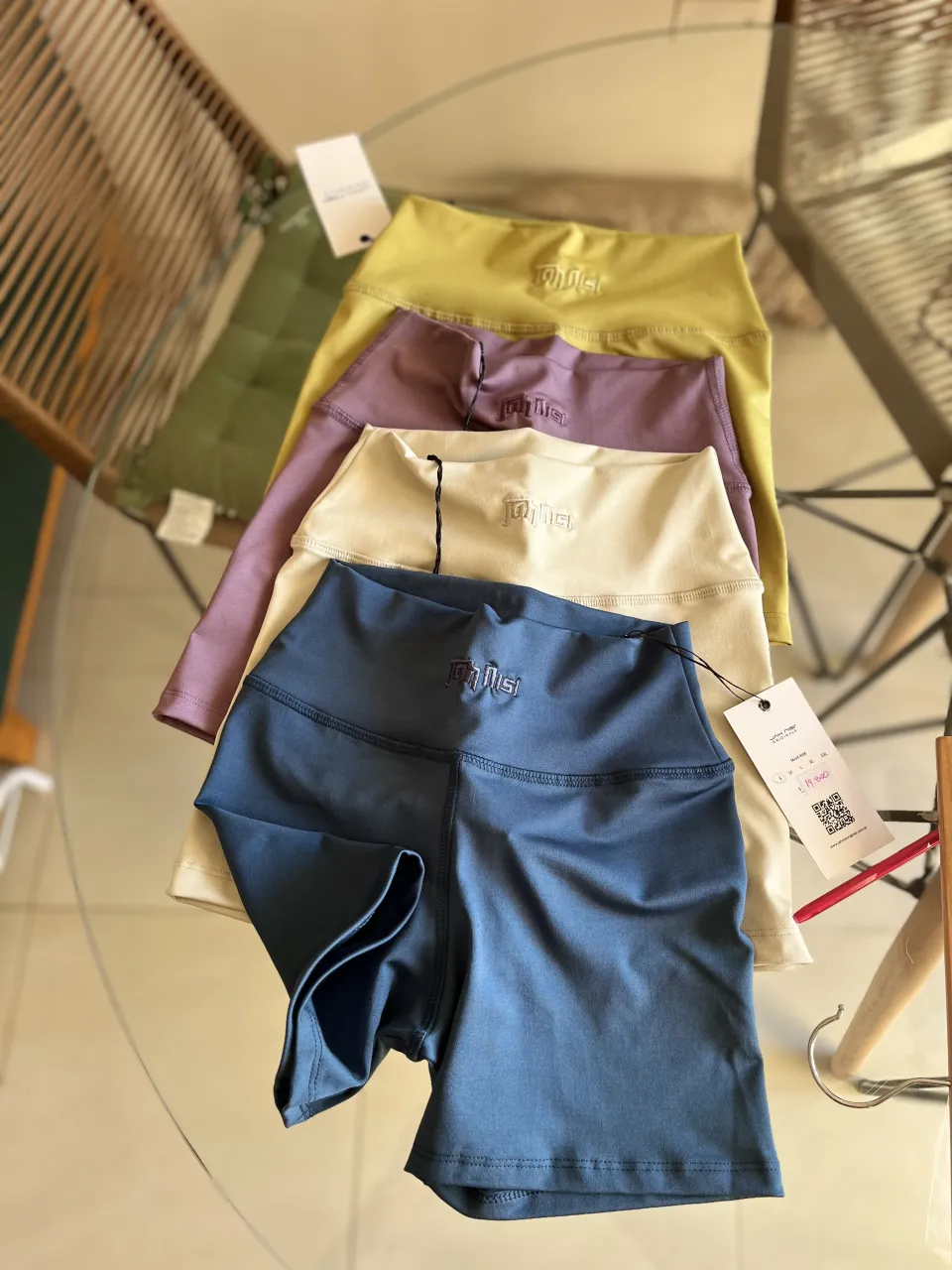 Shorts deportivos de tiro alto en varios colores: azul, crema, lila y amarillo. Presentan un logo bordado en la cintura.