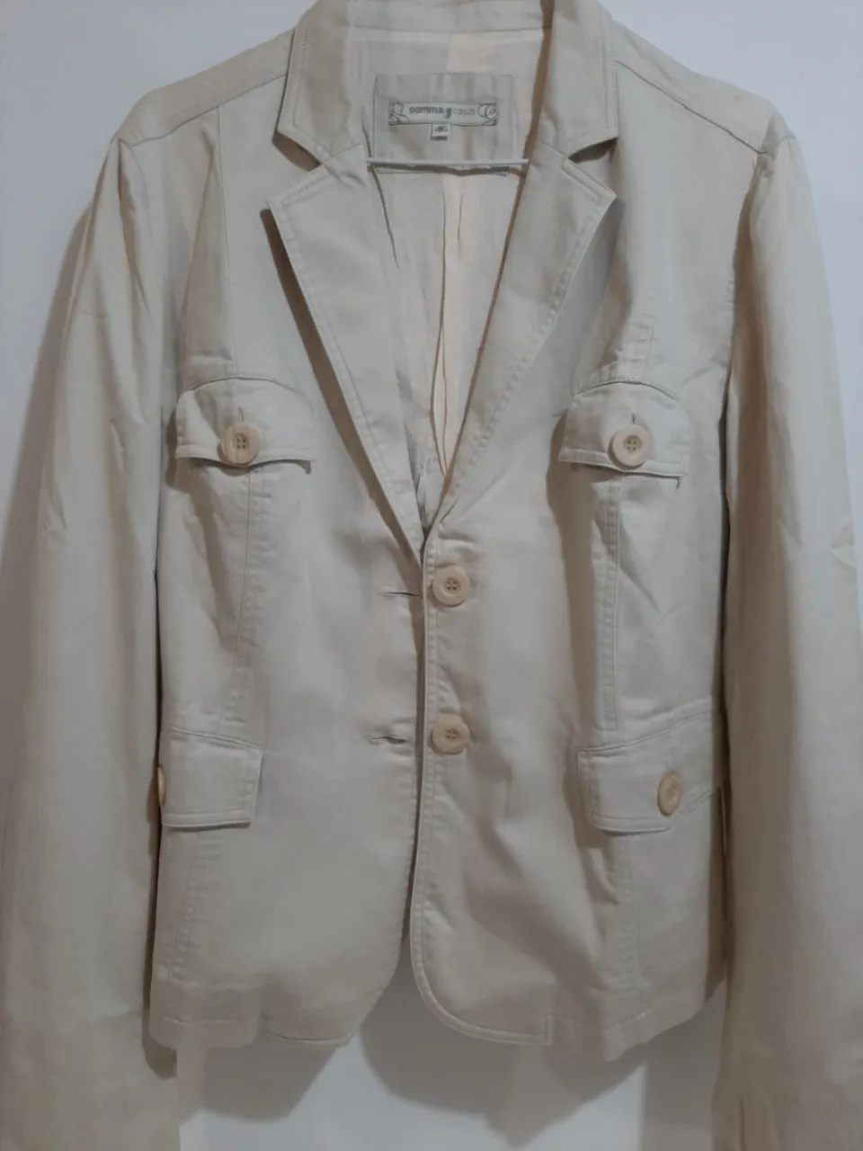 Blazer de tela color crudo, con botones al frente y bolsillos con tapa. Ideal para un look casual o de trabajo.