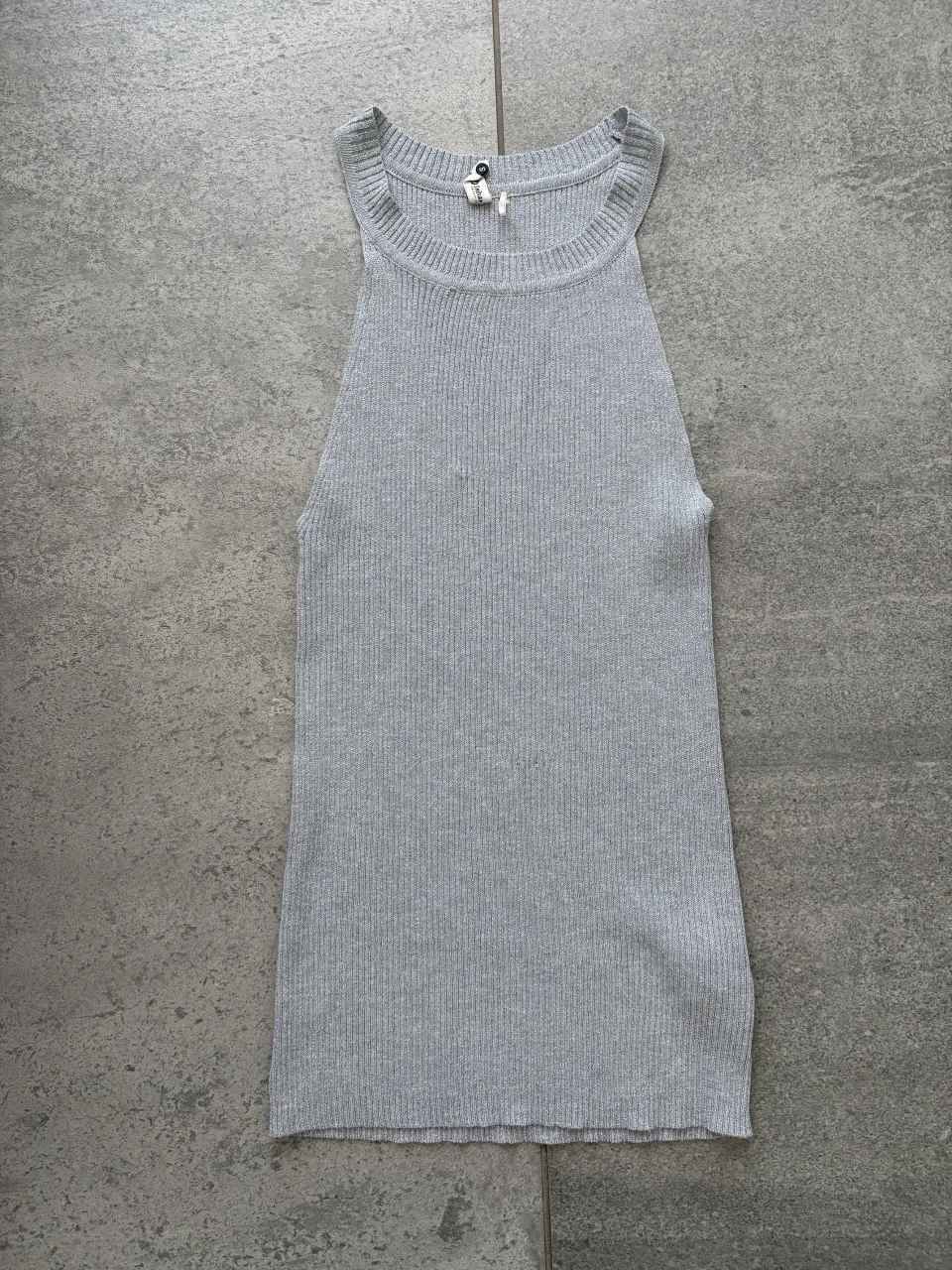 Musculosa de tejido de punto gris con brillos , cuello redondo y breteles anchos.