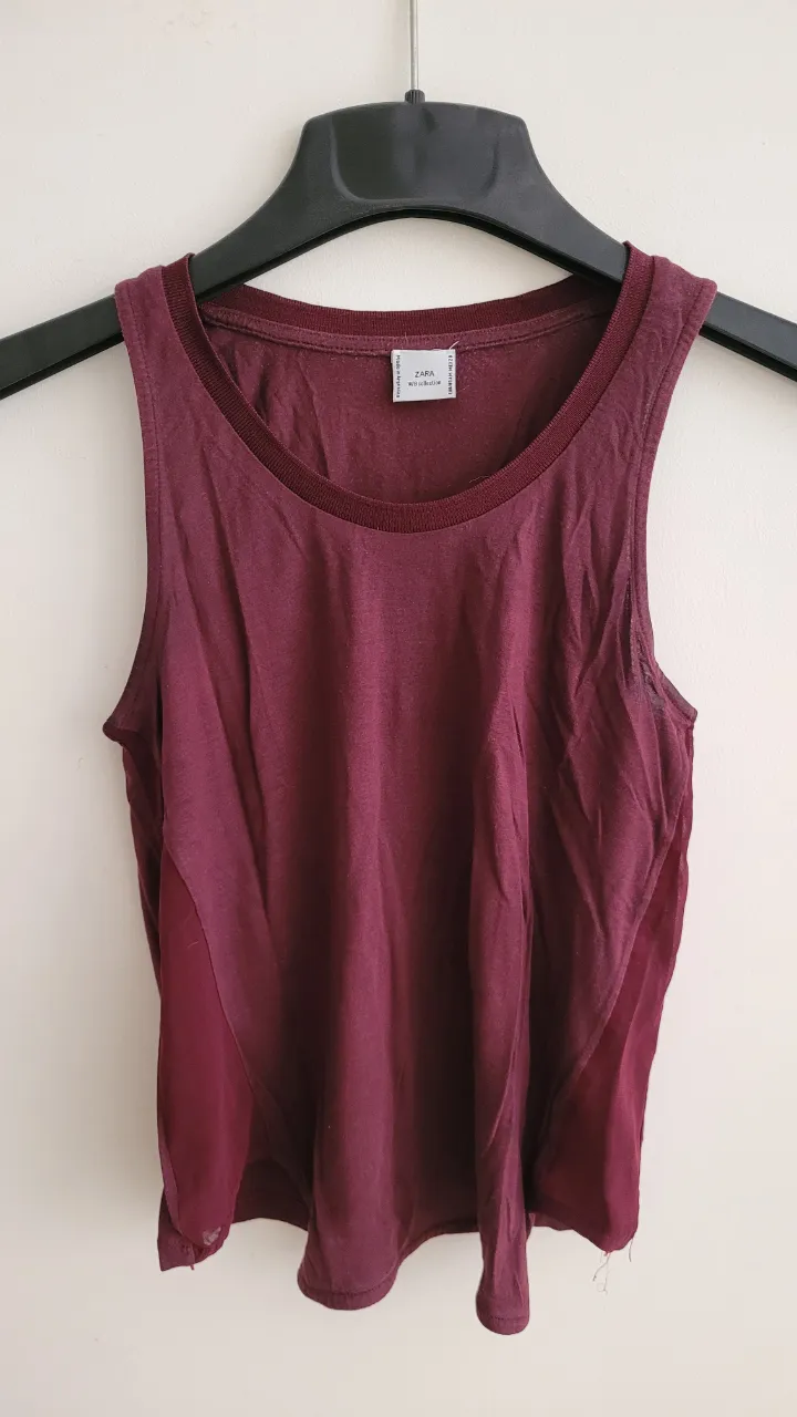 Musculosa de color bordo con detalles de tela transparente en los laterales. Cuello redondo.