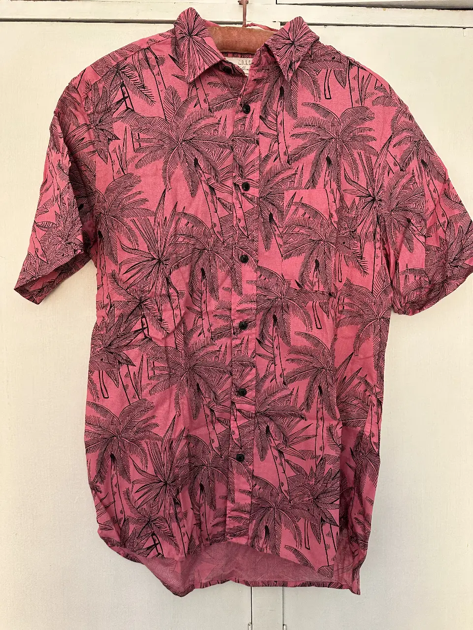 Camisa estampada con palmeras en color rosa, ideal para un look casual y fresco. Confeccionada en tela suave y cómoda, perfecta para el verano. Talle S.