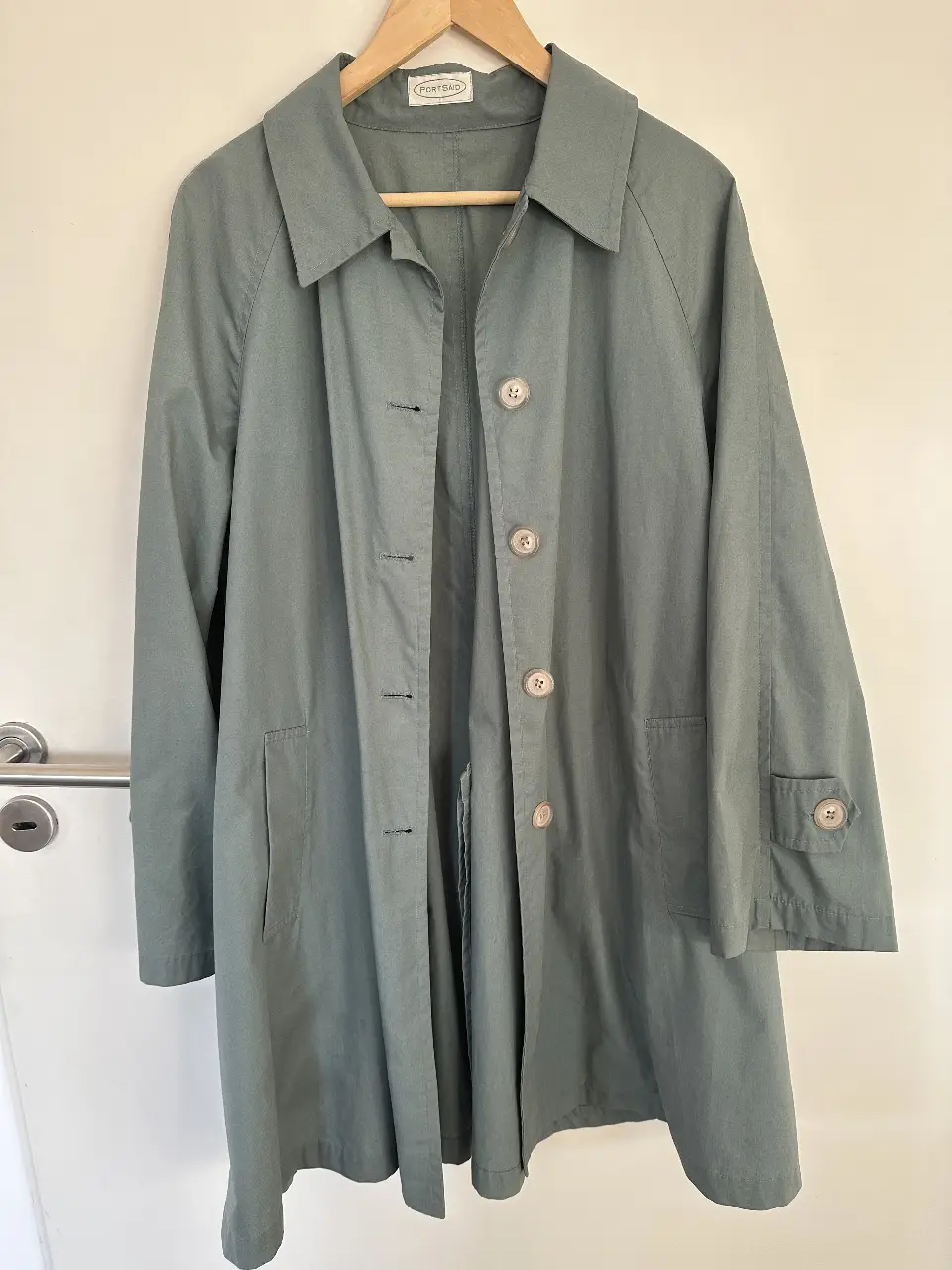 Trench coat verde claro de la marca PortsAid. Corte clásico, con botones y bolsillos. Ideal para un look casual y elegante. Le falta un botón en una manga