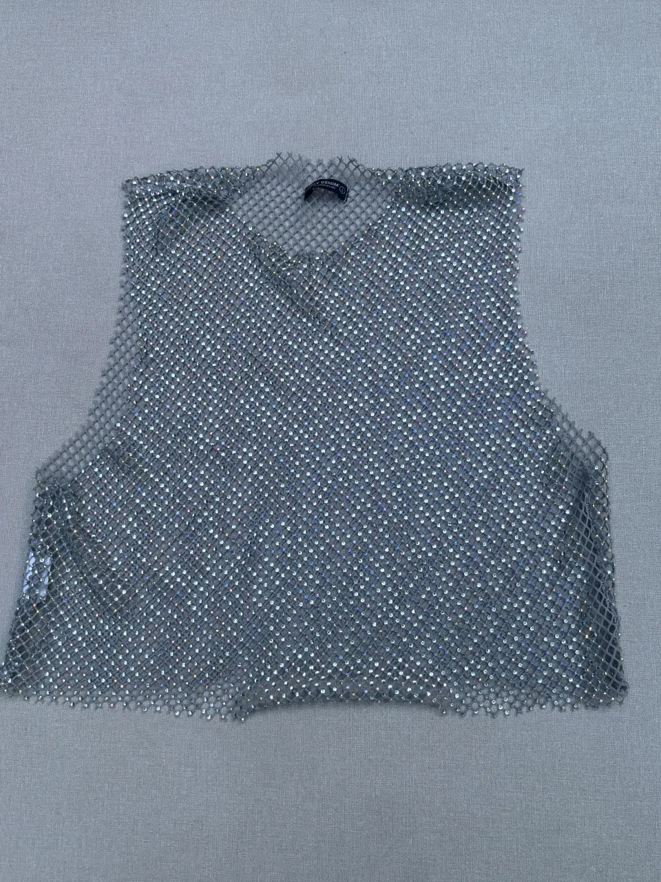 Top plateado con brillos, ideal para fiestas o salidas nocturnas. Su diseño calado y brillante lo hace perfecto para destacar en cualquier evento.