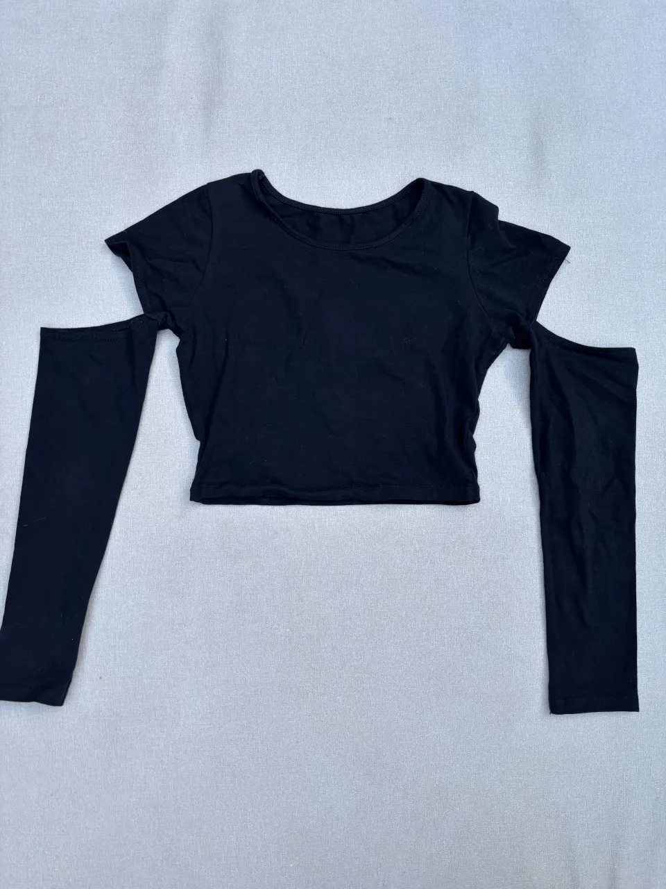 Remera negra manga larga con recortes en los hombros. Diseño moderno y canchero, ideal para un look urbano y a la moda.