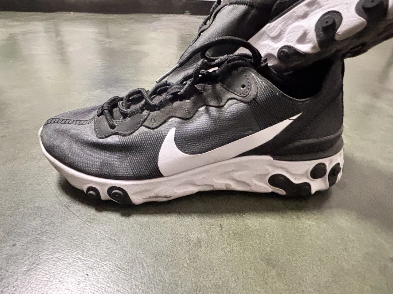 Zapatillas deportivas Nike React color negro y blanco. Poseen cordones negros y el logo de Nike blanco en el lateral.