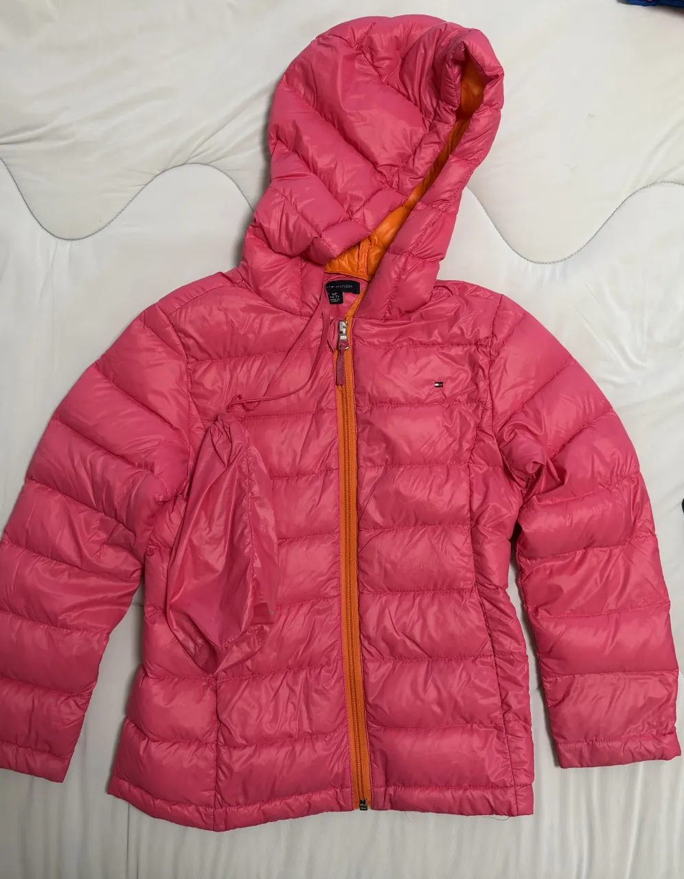 Campera acolchada rosa con capucha y cierre naranja. Interior naranja.