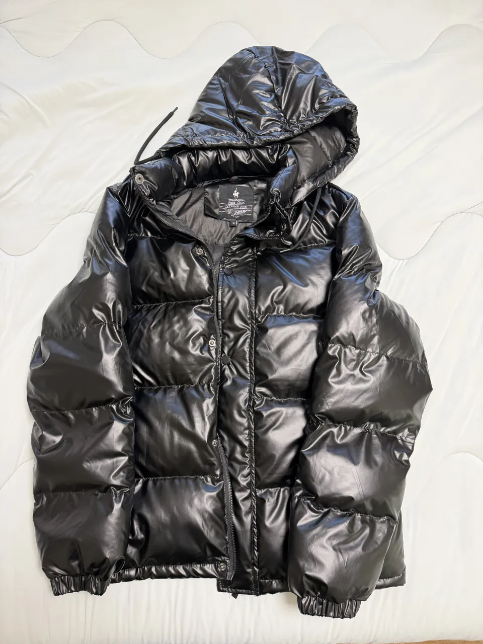 Campera negra acolchada con capucha. Cierre al frente y bolsillos laterales.