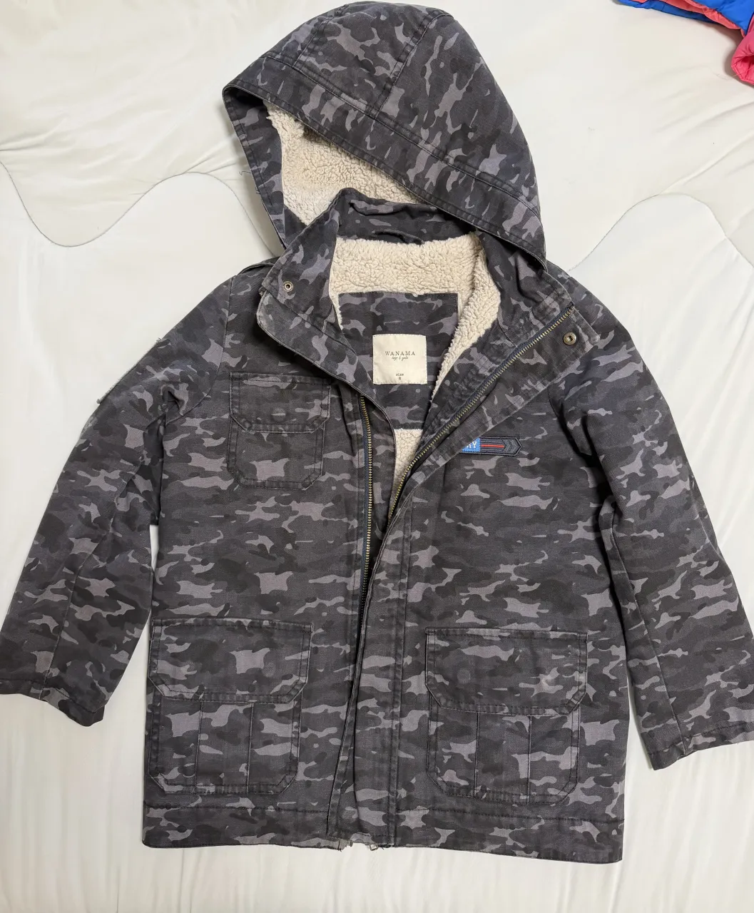 Campera de jean con capucha forrada en corderito. Estampado camuflado en tonos grises y negros. Cierre delantero y bolsillos con solapa.