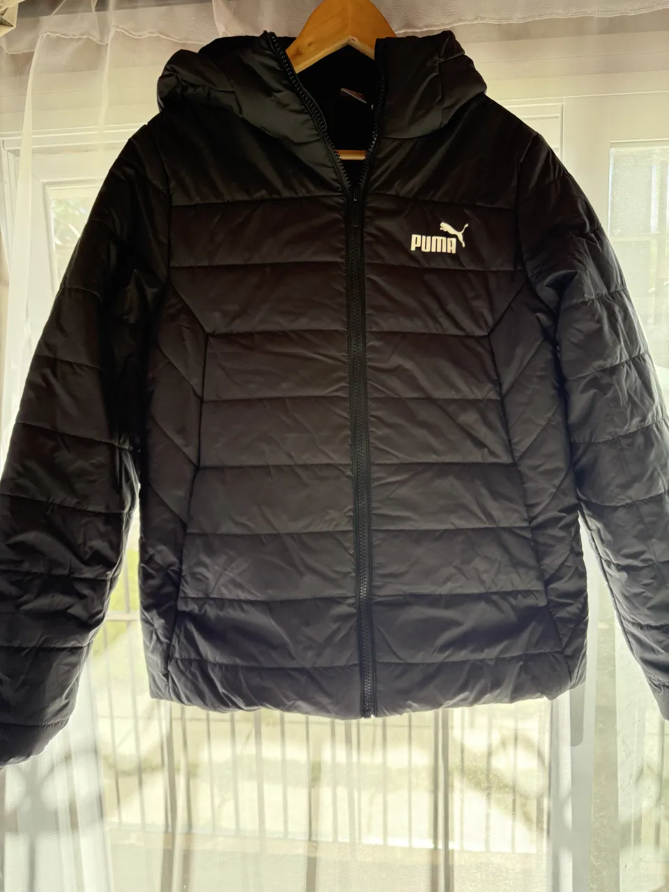 Campera negra acolchada con capucha. Tiene cierre al frente y logo de la marca en el pecho y en la espalda.