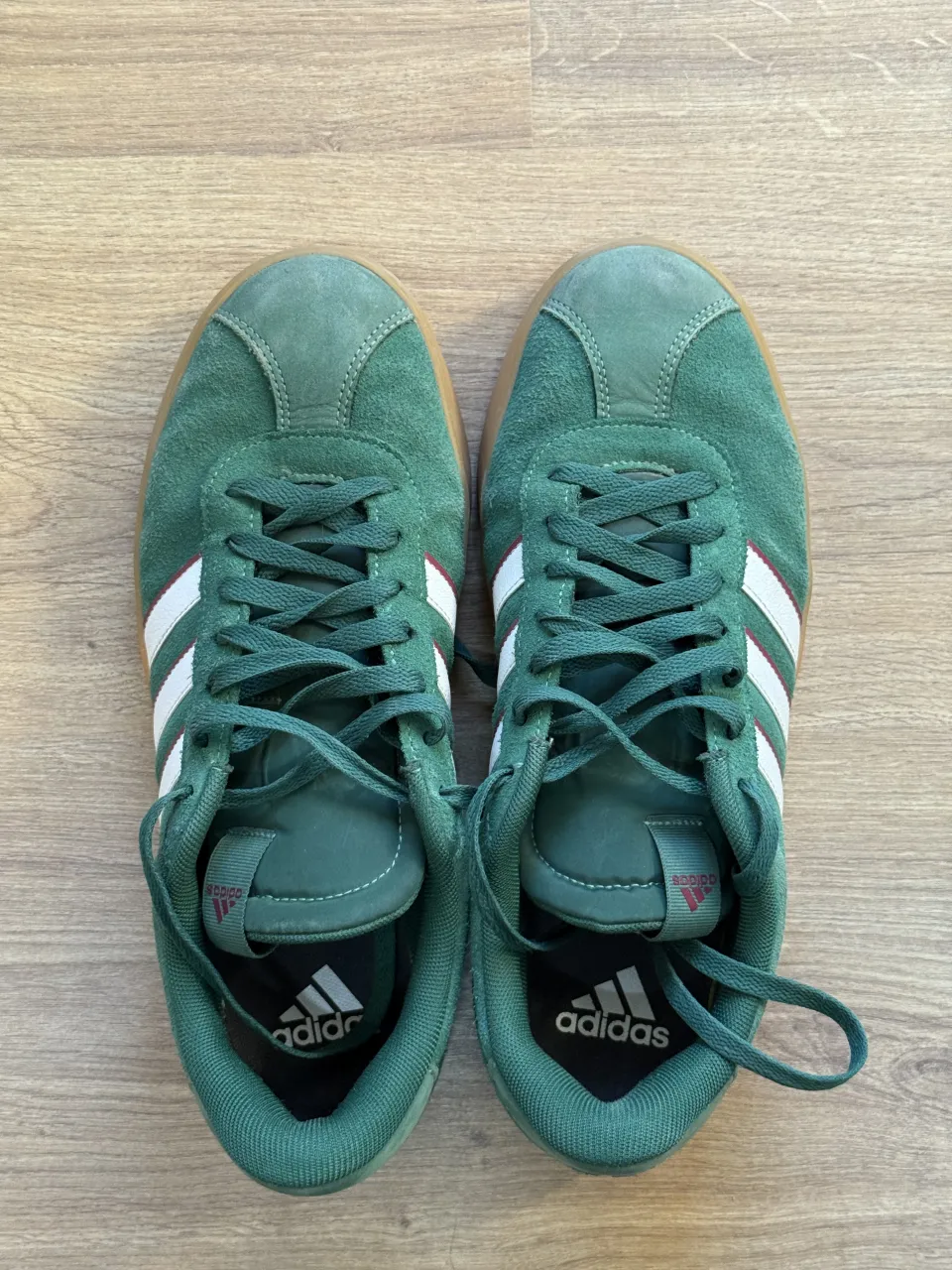 Zapatillas deportivas verdes con detalles blancos y suela de goma color caramelo. Marca Adidas.