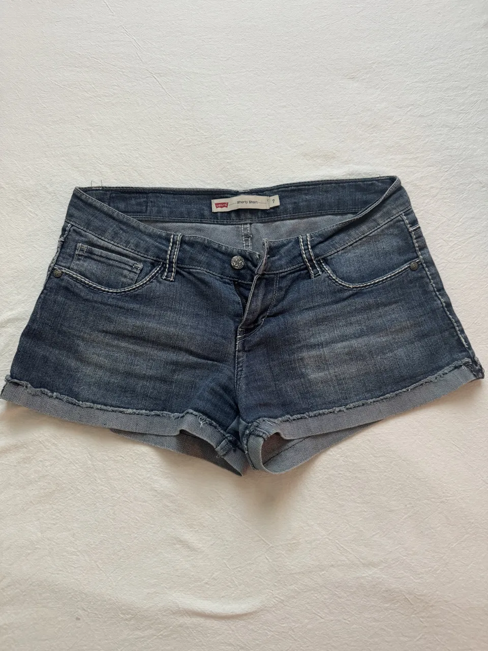 Shorts de jean azul con detalles de costura blanca y bolsillos traseros. La marca Levi's es visible en la etiqueta.