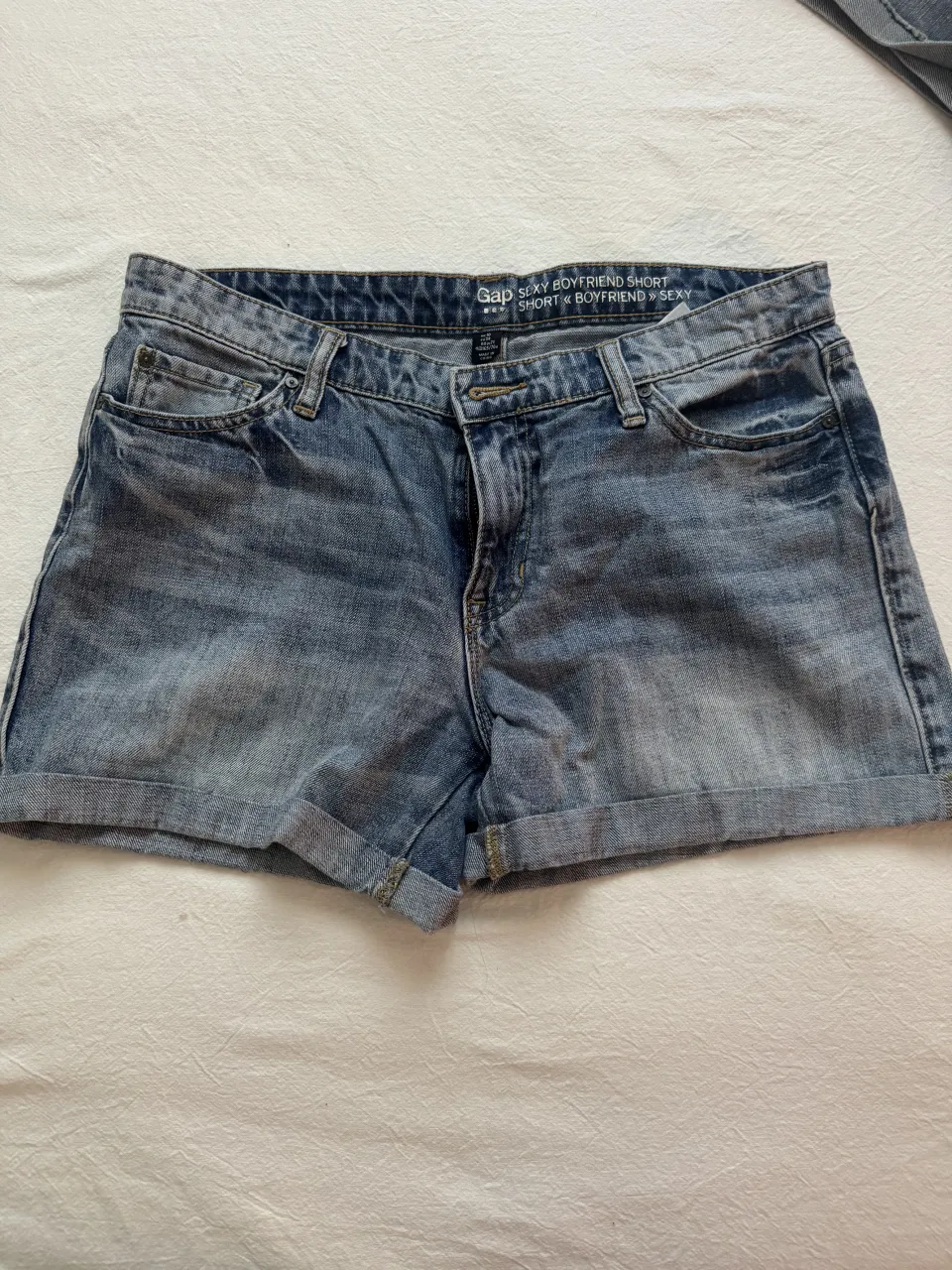 Shorts de jean tiro medio con dobladillo. Tiene bolsillos delanteros y traseros.