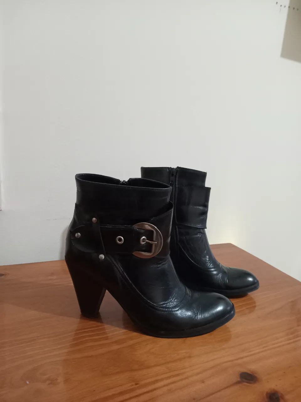 Botitas negras de cuero con hebilla y tachas. Cierre lateral.