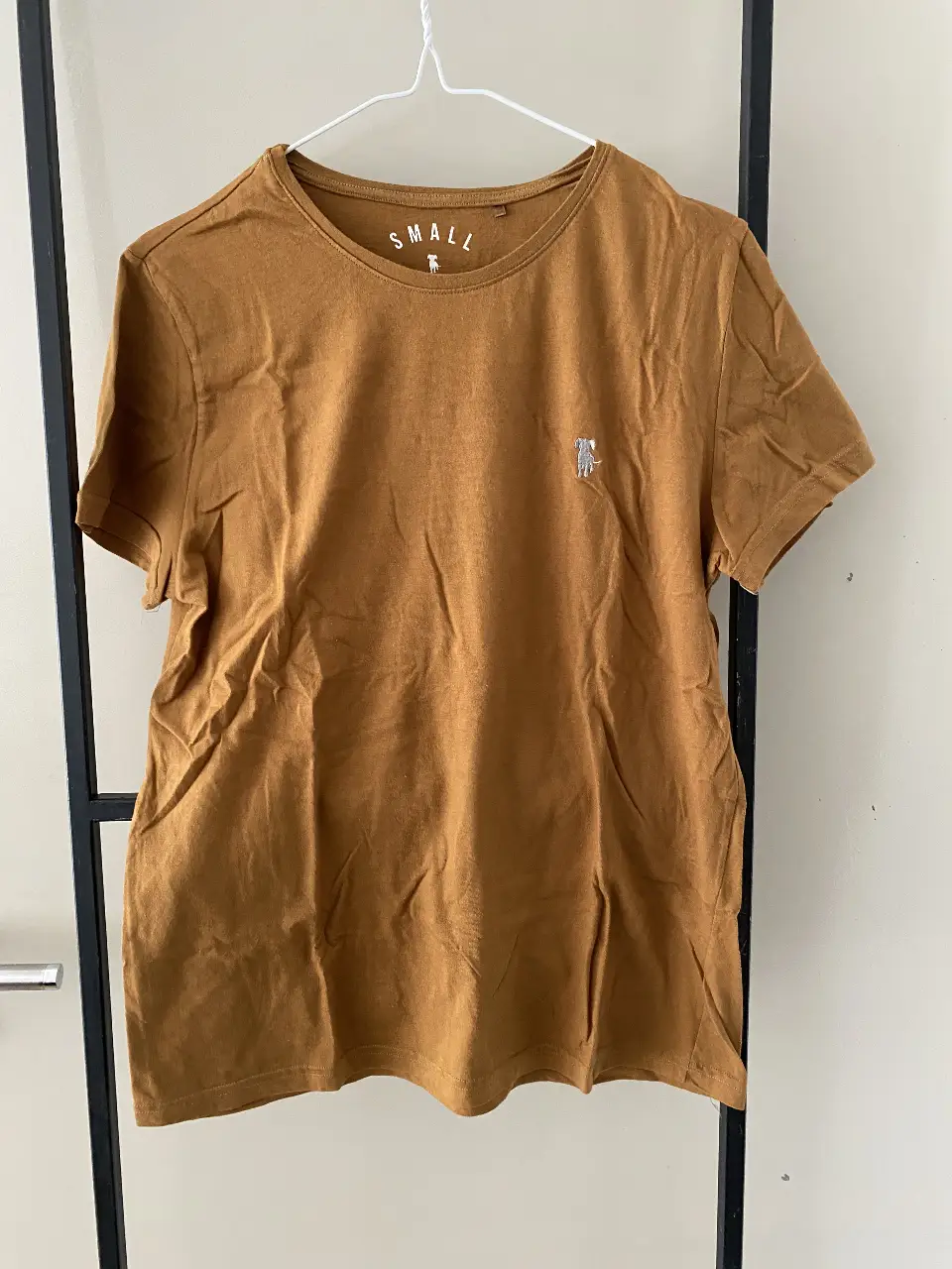 Remera manga corta color marrón, con detalle de bordado de un perro en el frente. Talle small. Ideal para un look casual y cómodo.
