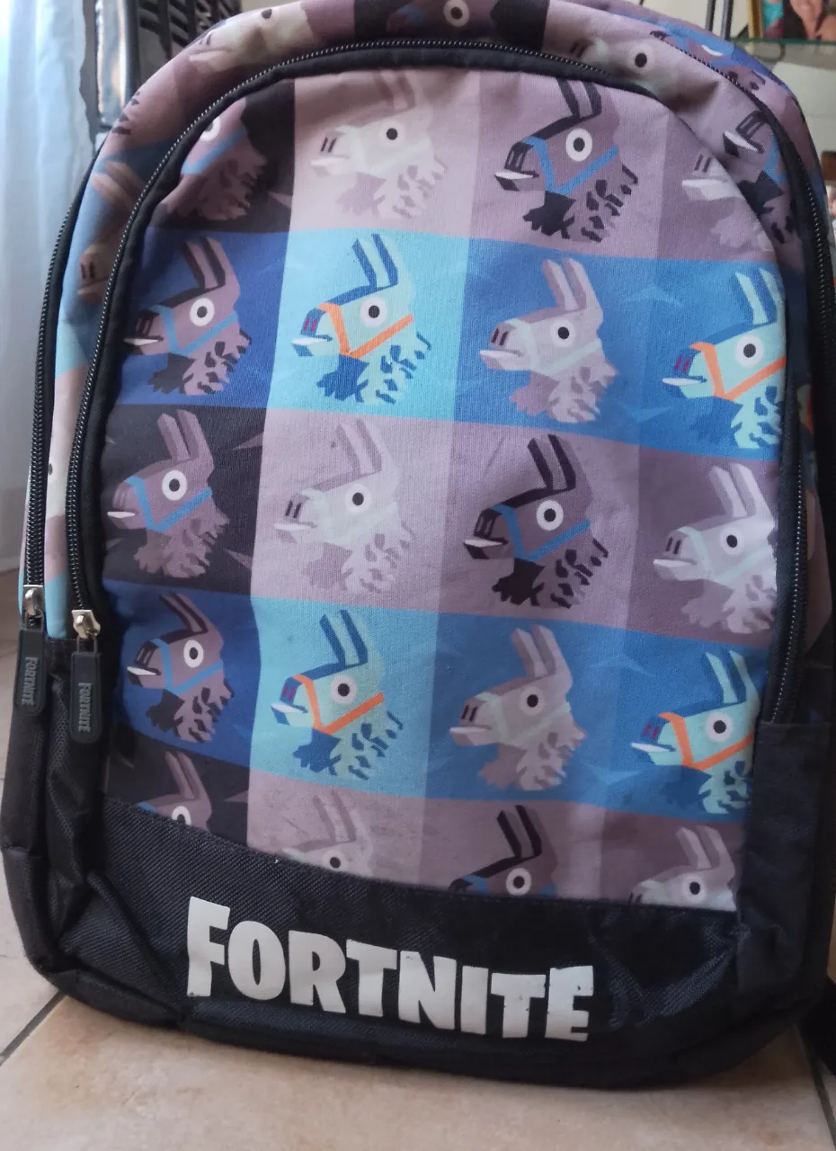 Mochila escolar con estampado de personajes de Fortnite. Tiene múltiples compartimentos con cierres y el logo de Fortnite en la parte frontal.