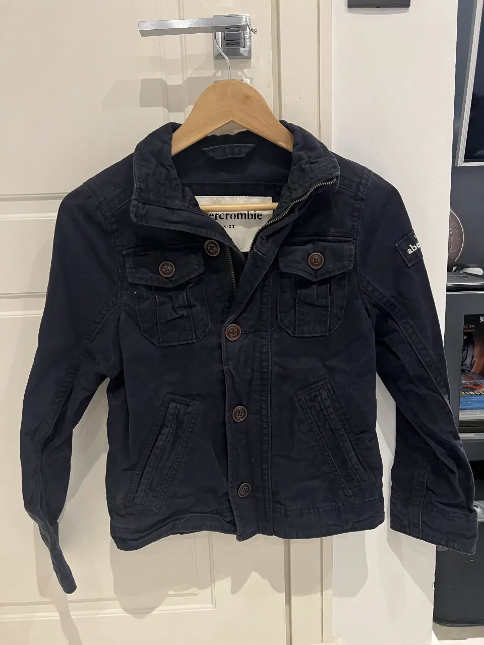 Campera Abercrombie Kids azul marino, estilo casual. Con botones y cierre, ideal para el día a día. es de niño talle M