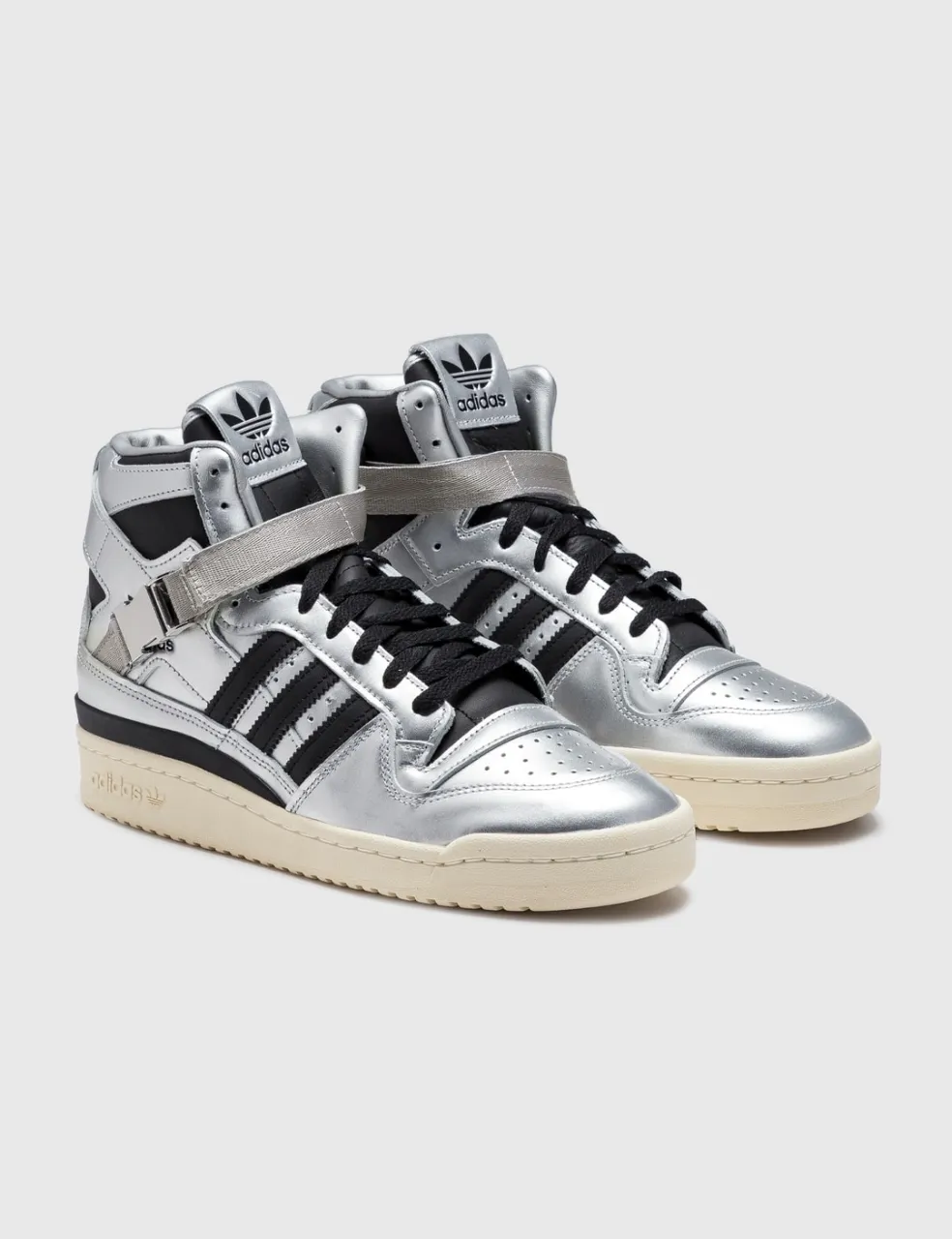 Zapatillas adidas de caña alta color plateado con detalles en negro y cordones negros. Tienen un velcro en la parte superior y el logo de la marca en la lengüeta.