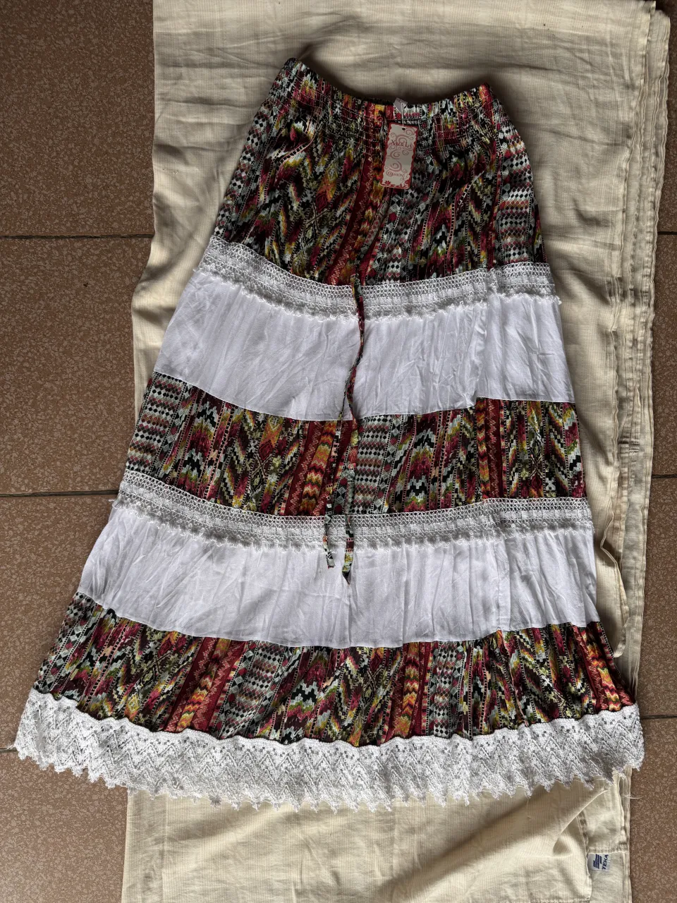 Pollera larga estampada con detalles de encaje blanco y fruncidos. Posee cintura elastizada con cordón. Talle S-M 