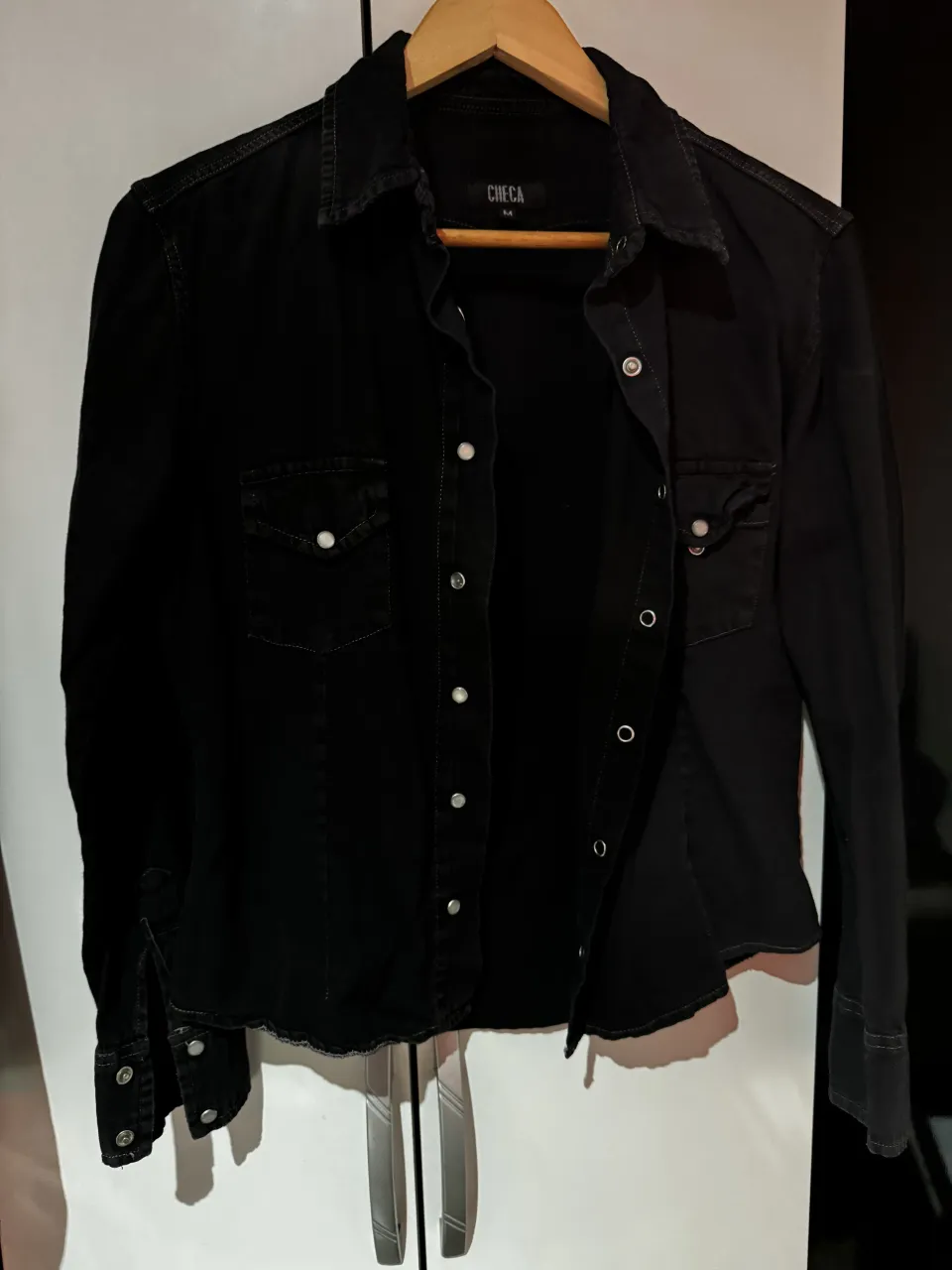 Camisa de jean negra, con botones metálicos y bolsillos en el frente. talle M tirando a S