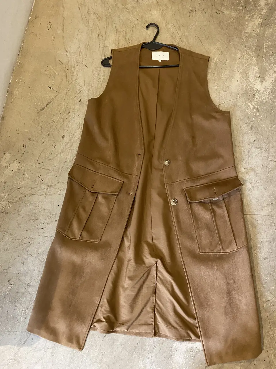 Chaleco largo de mujer, color marrón, con dos bolsillos delanteros y dos botones. Ideal para un look elegante y sofisticado.