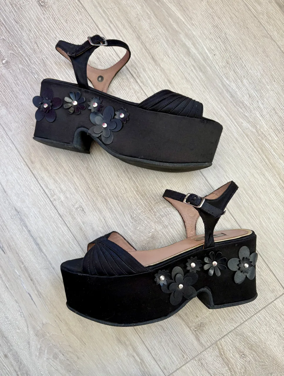 Sandalias negras con plataforma altísima y taco. Tienen detalles de flores en 3D en la parte delantera de la plataforma y una tira fina con hebilla para ajustar al tobillo. Ideales para darle un toque audaz y femenino a cualquier look.
Medida plantilla 24 cm, taco 8 cm.
