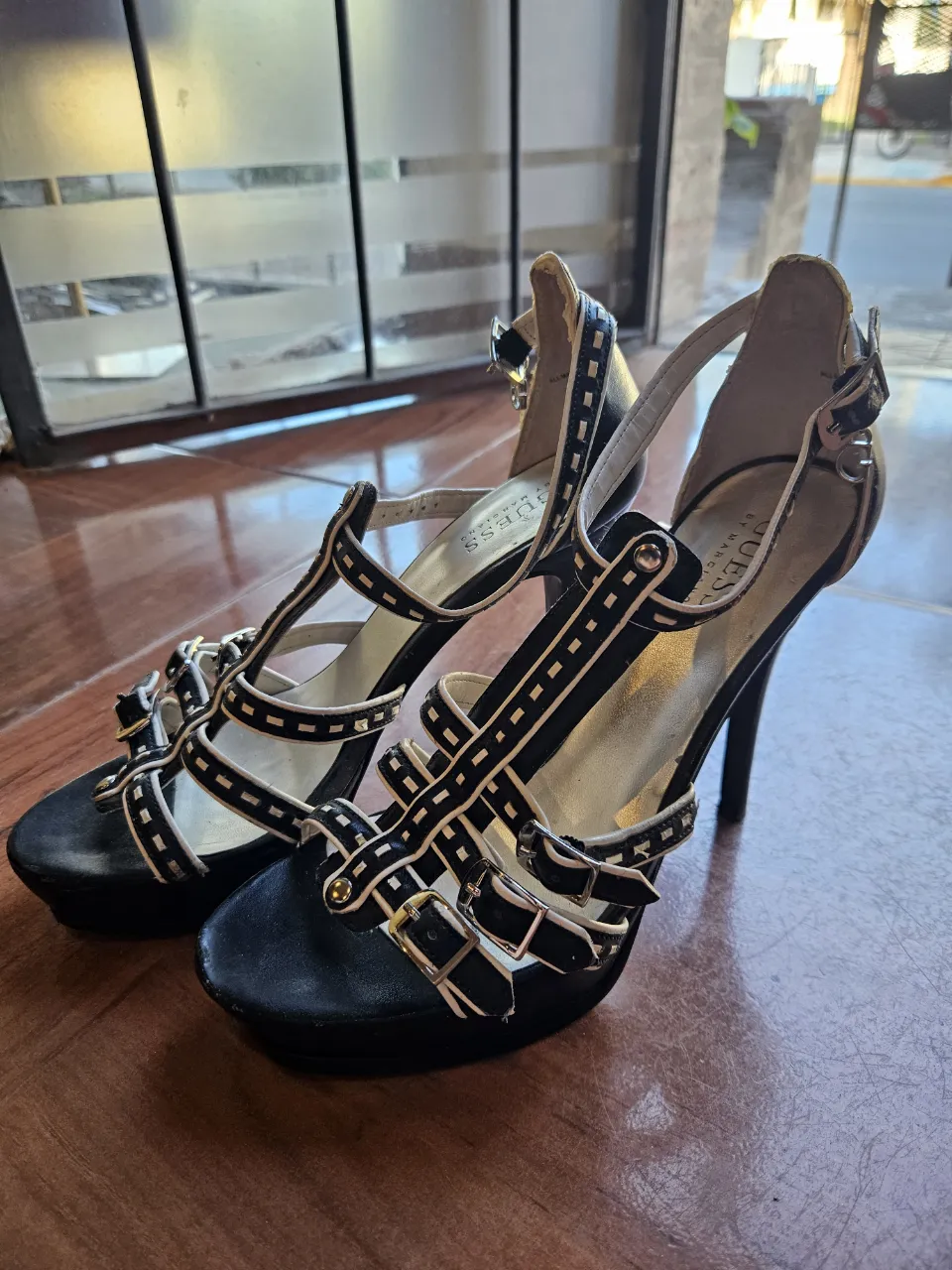 Sandalias de taco alto negras con tiras y hebillas. Marca Guess.