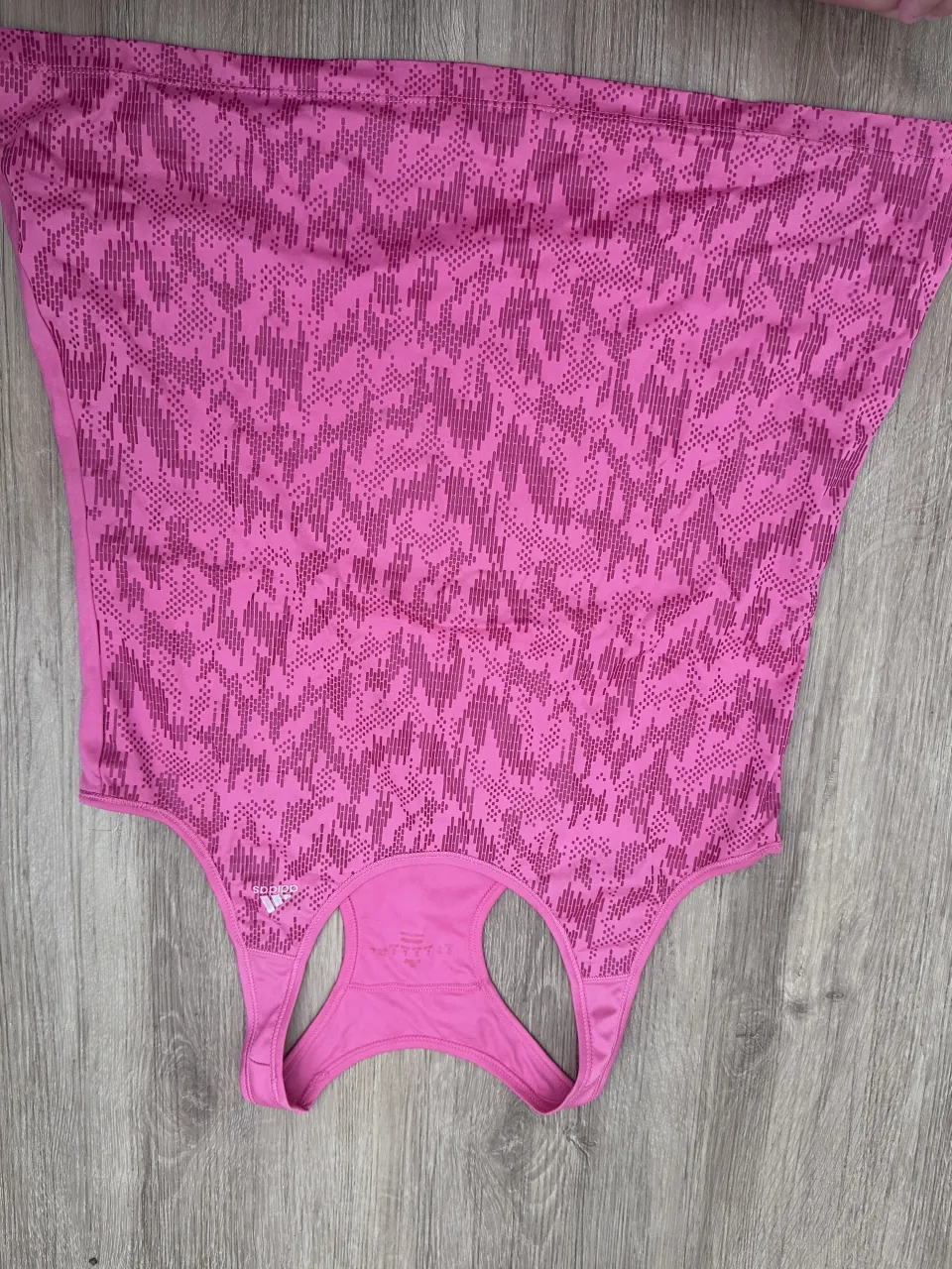 Musculosa deportiva rosa con estampado abstracto en tonos de rosa más oscuro. Posee logo de la marca en la parte delantera.