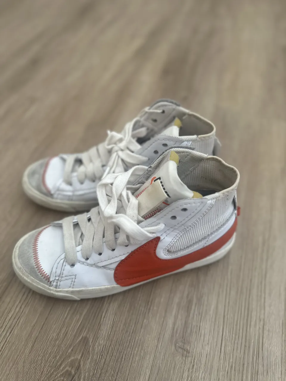 Zapatillas de caña alta blancas con detalles en rojo y gris. Cordones blancos.