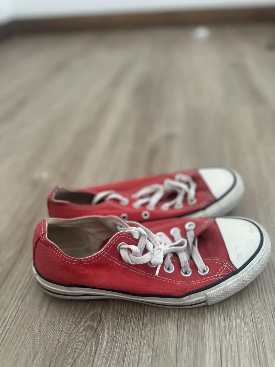 Zapatillas Converse rojas con cordones blancos.