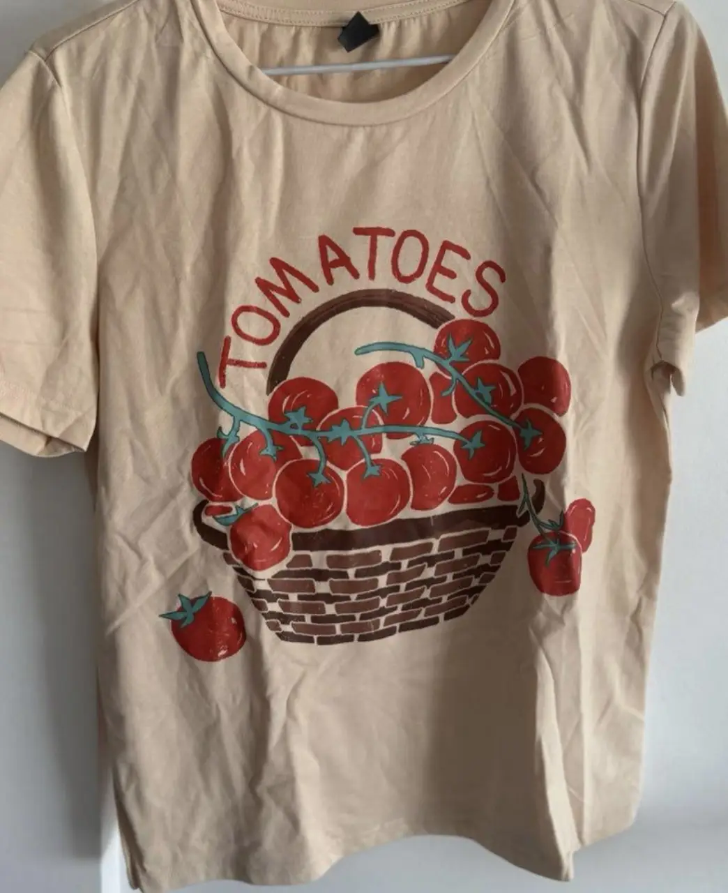Remera de algodón color crudo con estampado de canasta de tomates. Ideal para un look casual y fresco.