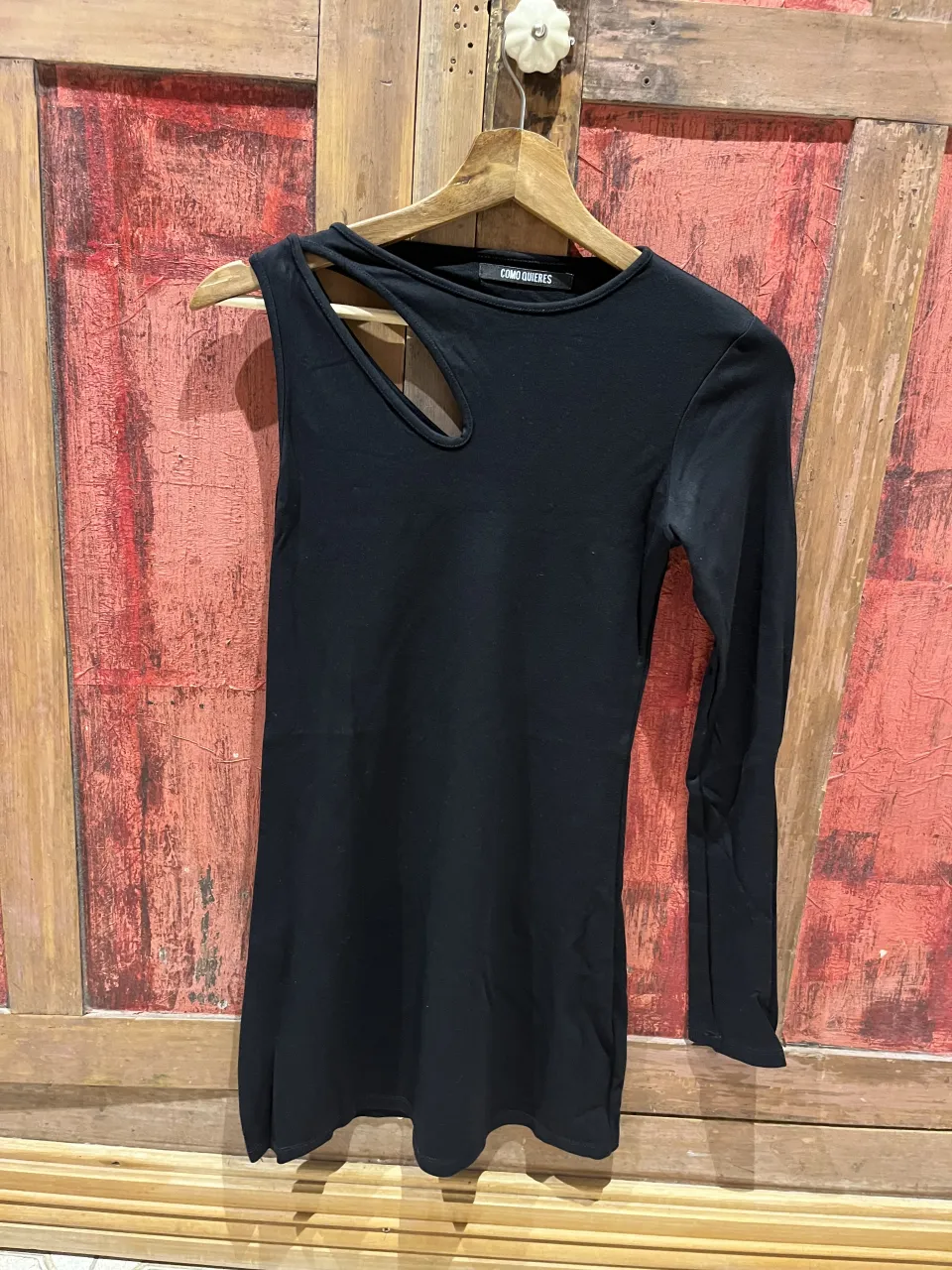 Remera negra de manga larga con recorte asimétrico en el hombro y escote redondo.