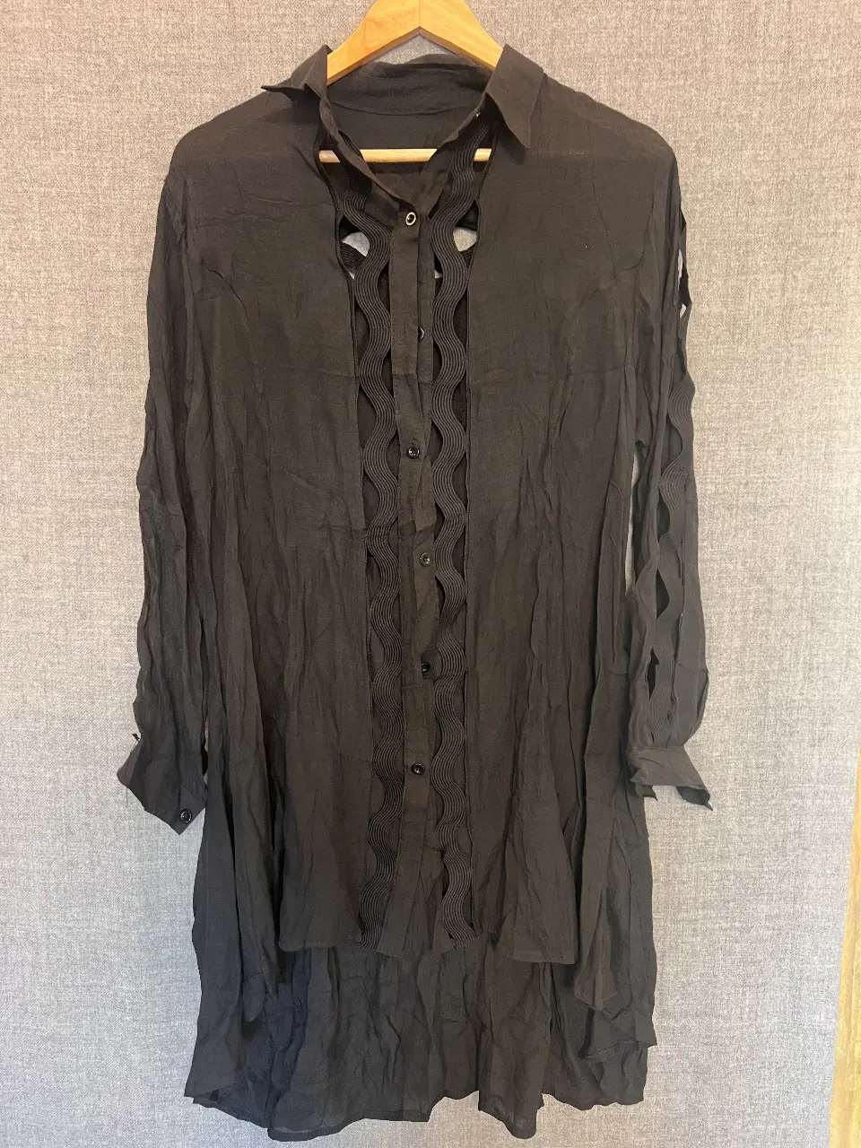 Camisa negra con detalles calados en el frente y espalda. Mangas largas con detalles en los hombros y puños. Ideal para un look elegante y sofisticado.