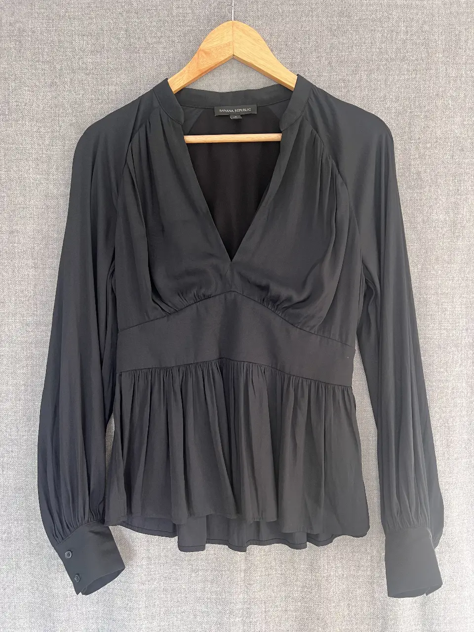 Blusa negra de manga larga con detalle de fruncido en el pecho y cintura. Ideal para un look elegante y sofisticado.