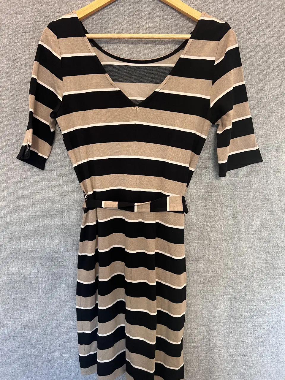 Vestido a rayas horizontales en negro, blanco y beige. Con cinturón para ajustar la cintura y mangas cortas. Ideal para un look casual y elegante.