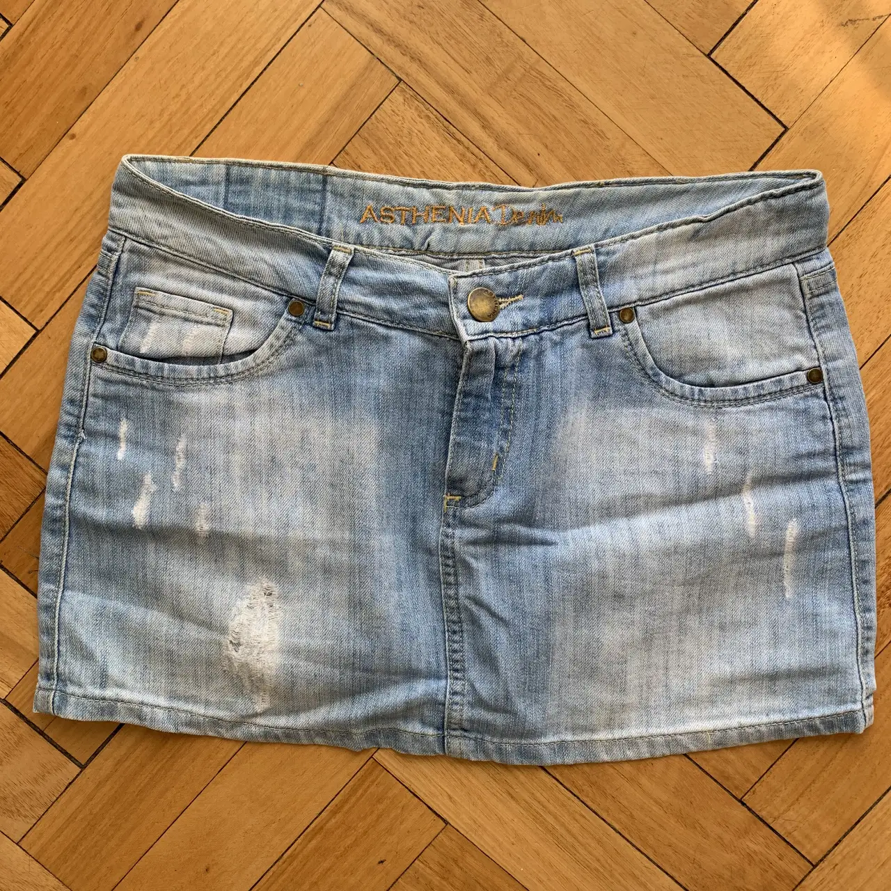 Minifalda de jean azul claro con detalles de roturas y desgaste. Ideal para un look casual y moderno.