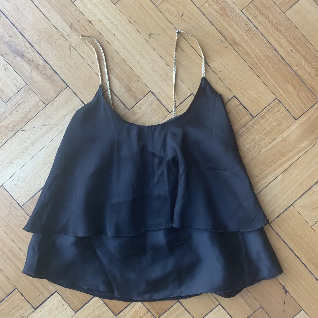 Top negro con tiras doradas y diseño de volados. Ideal para un look de fiesta o salida.