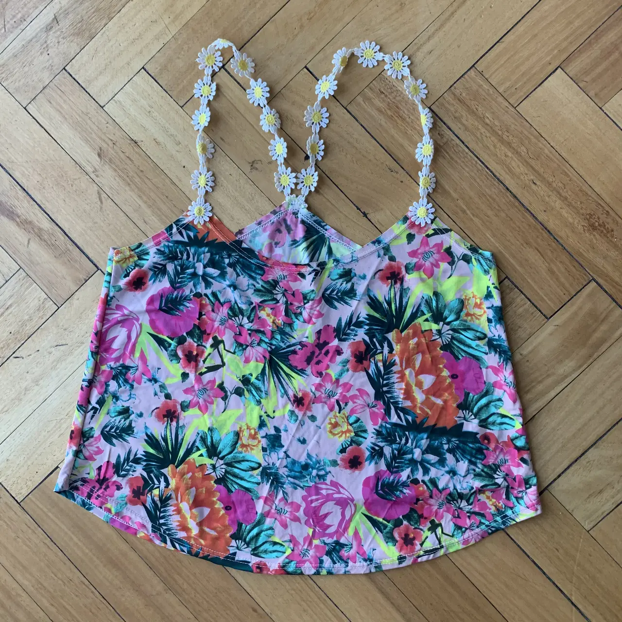 Top de mujer con estampado floral vibrante y tirantes decorados con flores. Ideal para un look fresco y primaveral.