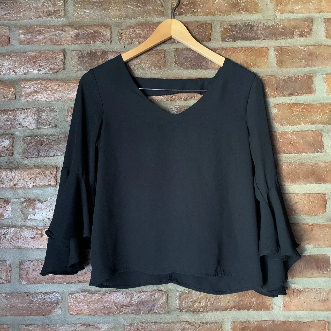 Blusa negra con mangas largas acampanadas y espalda descubierta. Ideal para un look elegante y moderno.
