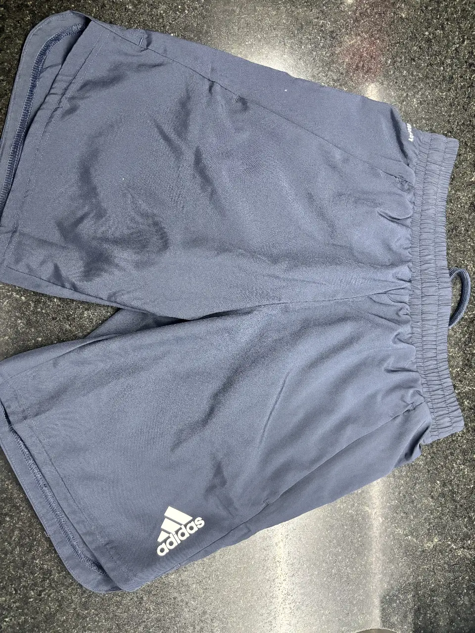 Short deportivo Adidas para hombre, color azul oscuro, con cintura elastizada y logo de la marca. Ideal para entrenamientos y actividades físicas.