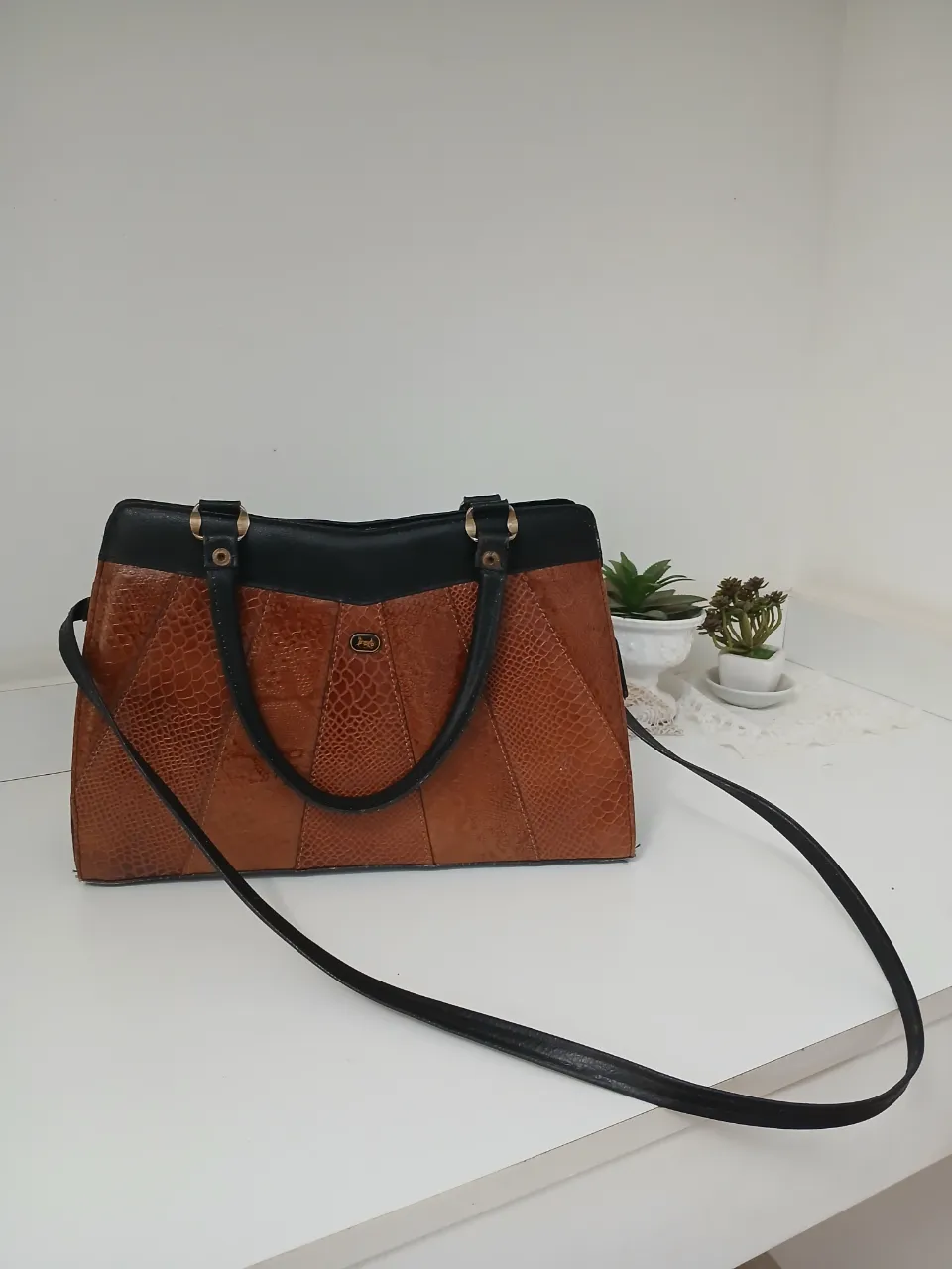 Bolso de cuero vacuno marrón con detalles en negro. Posee dos asas cortas y una correa larga desmontable. Tiene un logo ovalado con un carro y un caballo en la parte frontal. Es un tote vintage, en excelentes condiciones,  super cómodo.  