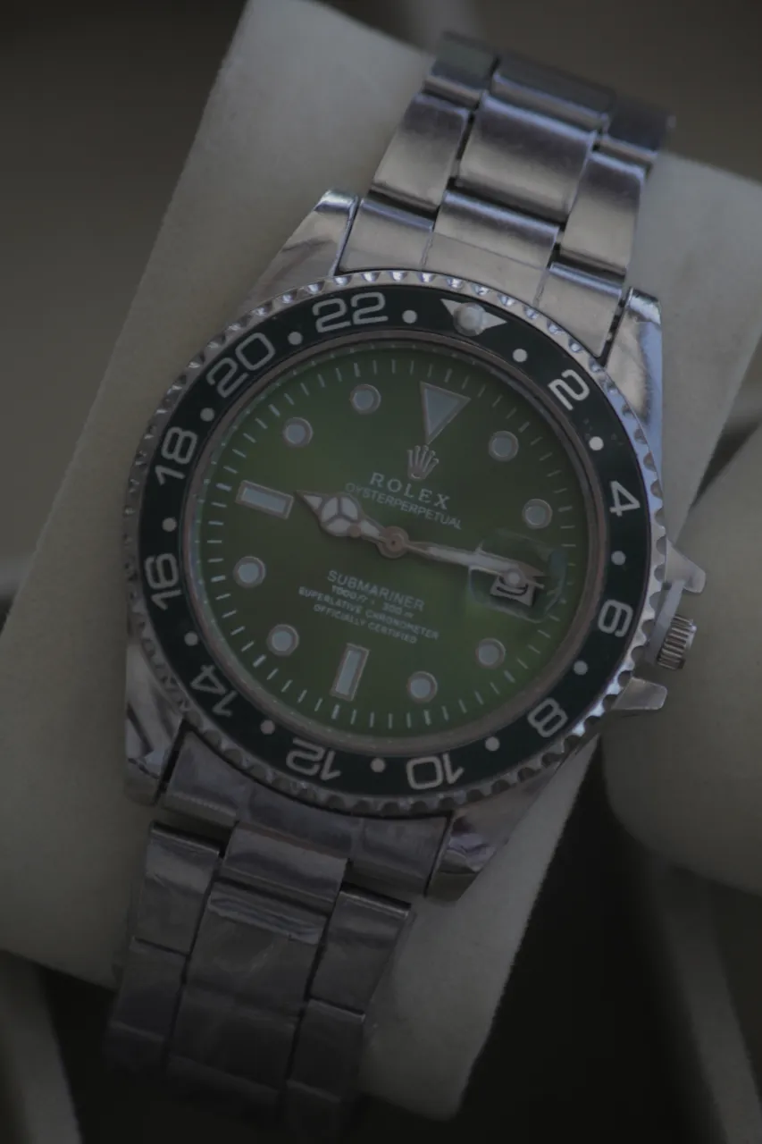 Reloj Submariner con malla de acero y bisel verde. Esfera verde con detalles plateados.