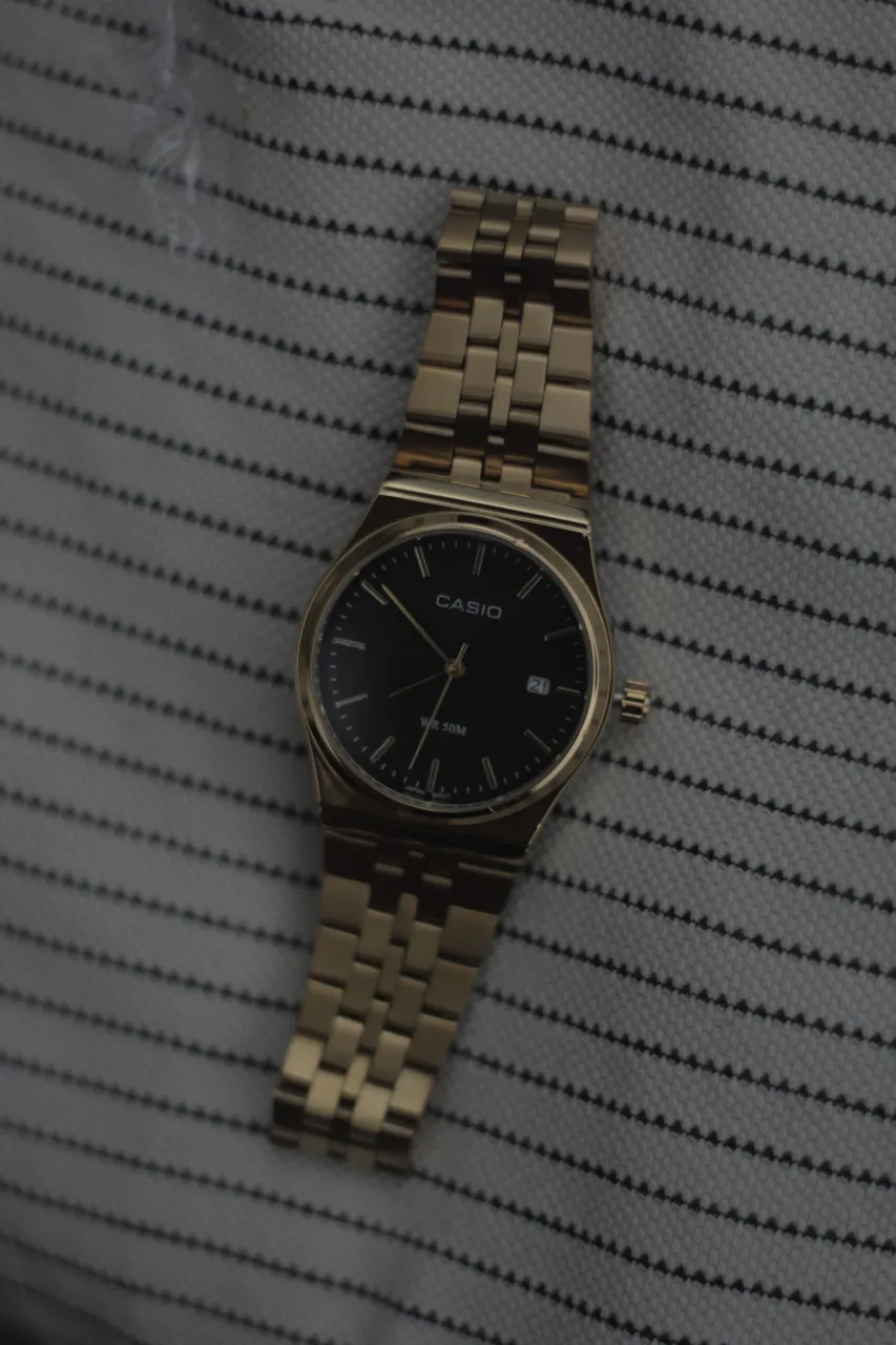 Reloj Casio dorado con malla de acero y cuadrante negro. Resistente al agua 50 metros.