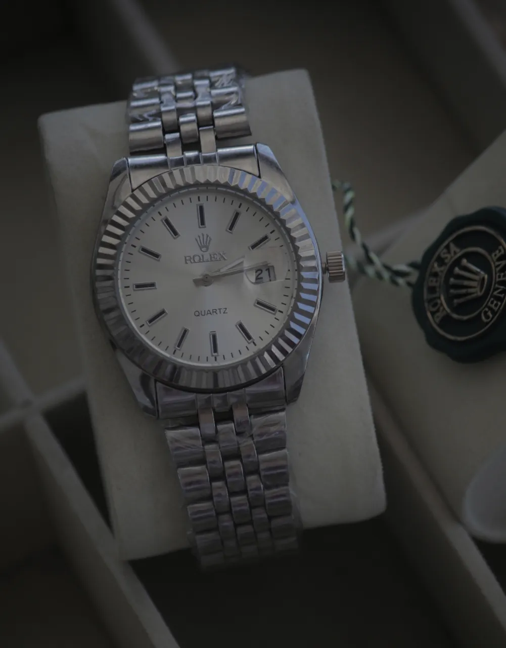 Reloj de pulsera plateado con malla metálica y cuadrante blanco. Presenta detalles de cronómetro y la marca visible en el cuadrante.