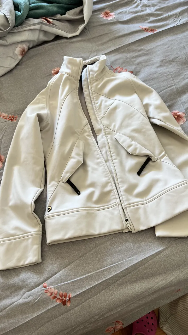 Campera deportiva blanca, ideal para actividades al aire libre o para un look casual y moderno. Cuenta con bolsillos frontales con cierres y un diseño moderno.