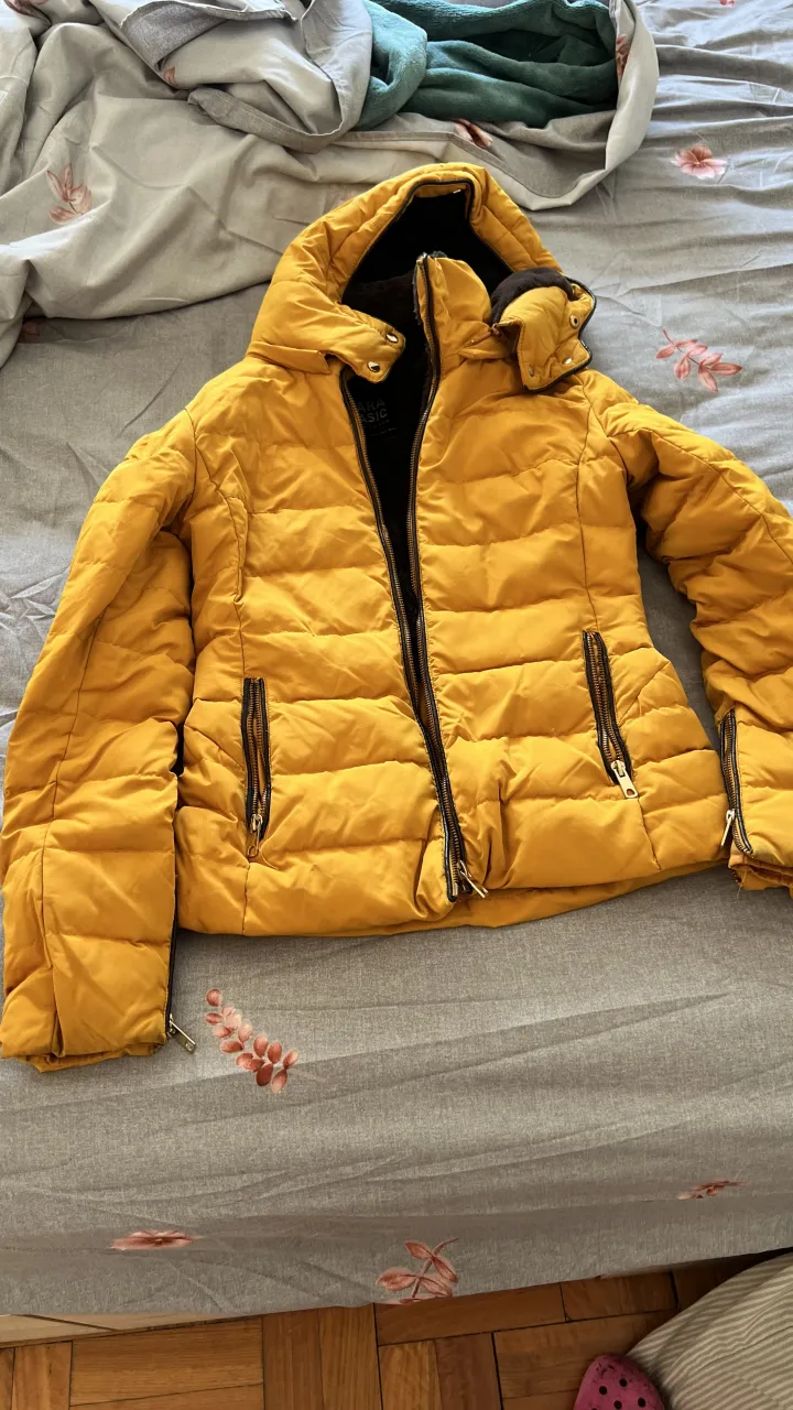 Campera puffer amarilla, súper abrigada y con forro interno de peluche. Ideal para los días más fríos, tiene bolsillos con cierre y capucha. ¡Un básico para tu guardarropas!