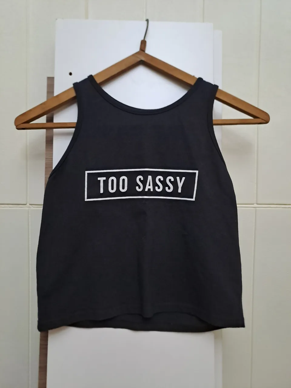 Musculosa negra con estampa blanca "TOO SASSY" en el frente.