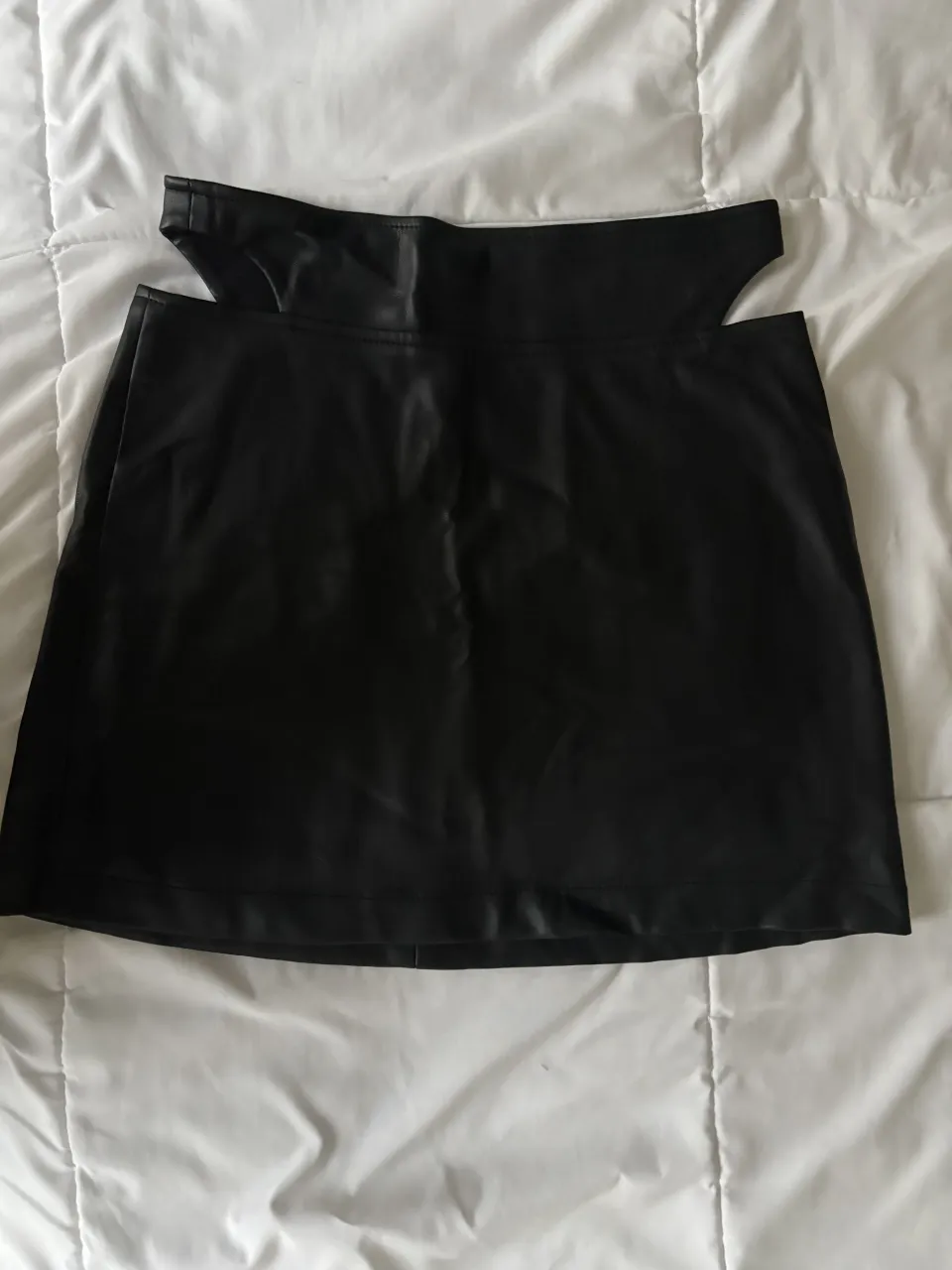 Pollera negra corta con recortes en la cintura y cierre en la espalda.